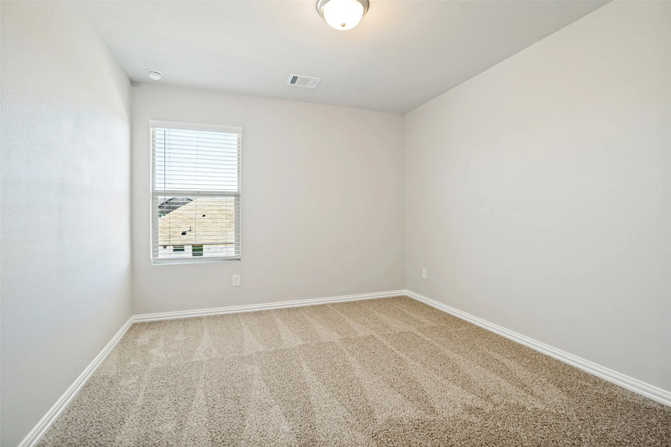 Neutral-toned carpeting, white walls, and a window with blinds