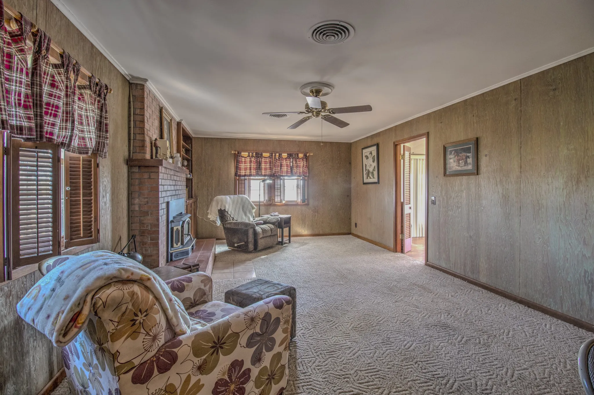 Spacious living room with a beautiful brick fireplace, abundant natural light and plenty of room for multiple seating areas.