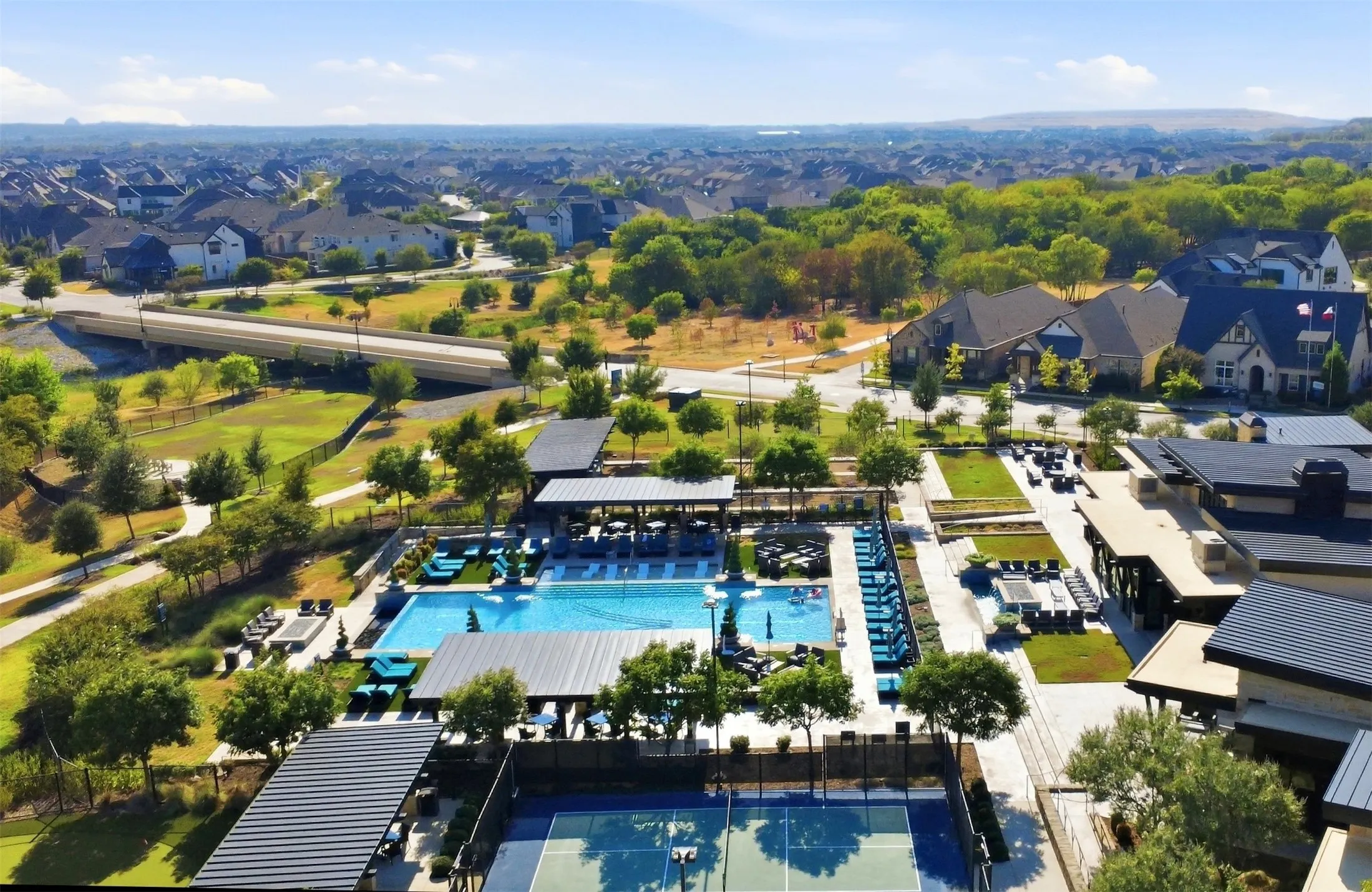 Outdoor recreational area featuring multiple swimming pools, tennis courts, and landscaped green spaces