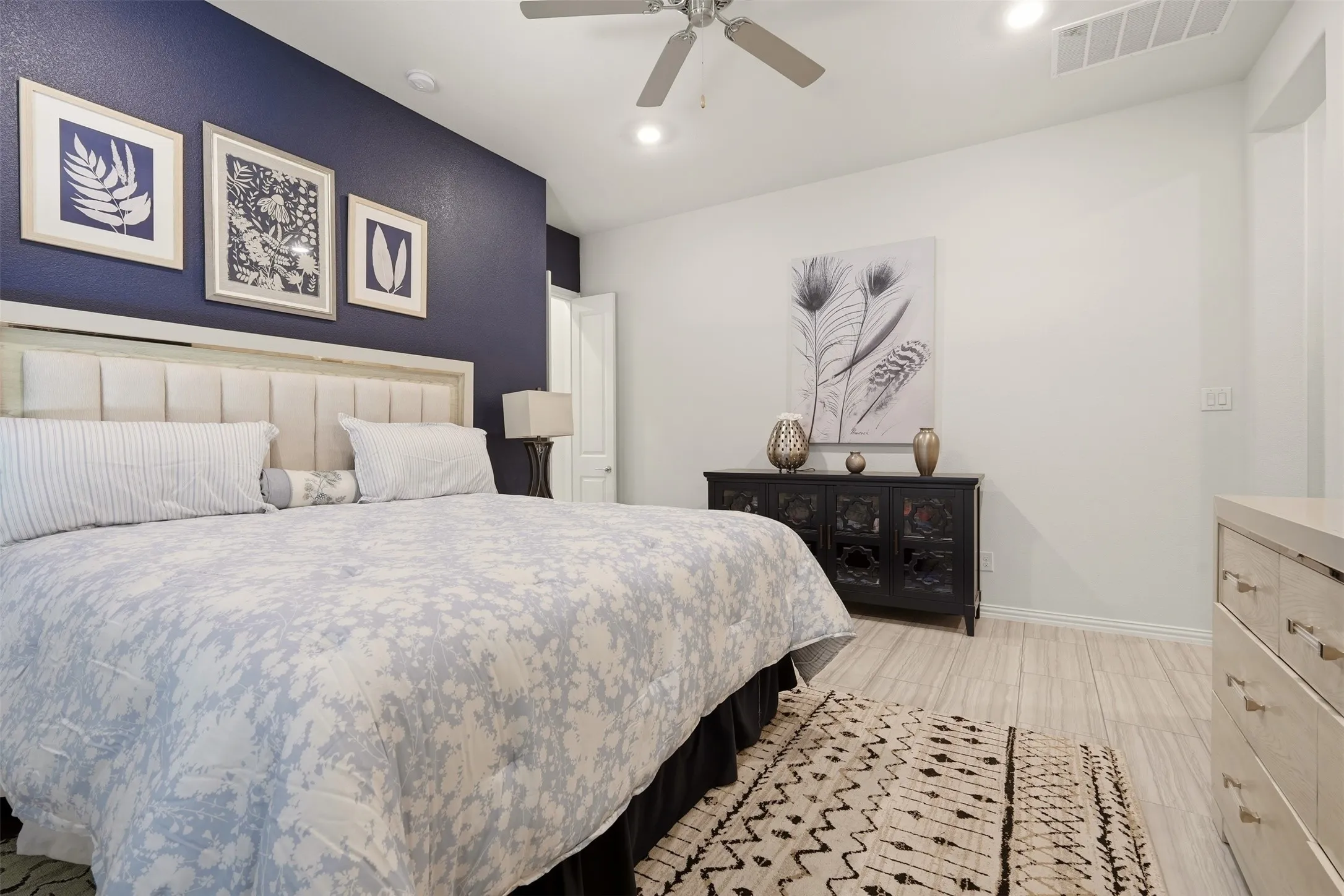 Recessed lighting, ceiling fan, wood-finish flooring, accent wall, and a paneled headboard