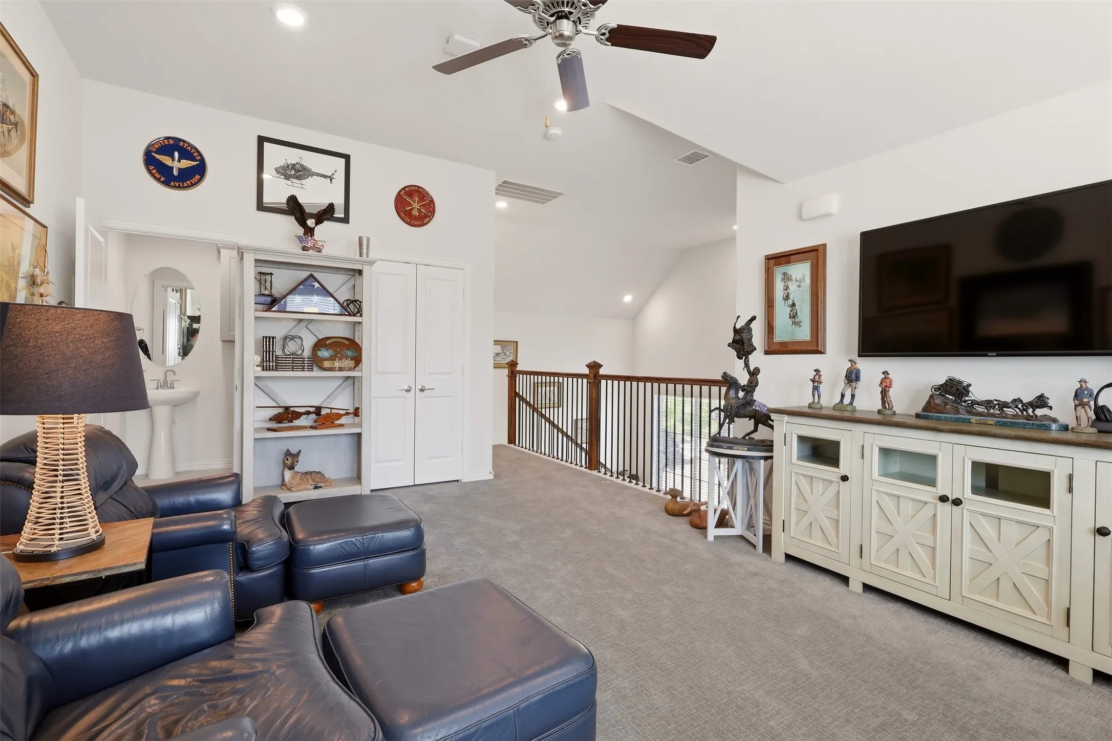 Vaulted ceiling with a ceiling fan, recessed lighting, carpet flooring, wood-finish railing, and built-in shelving