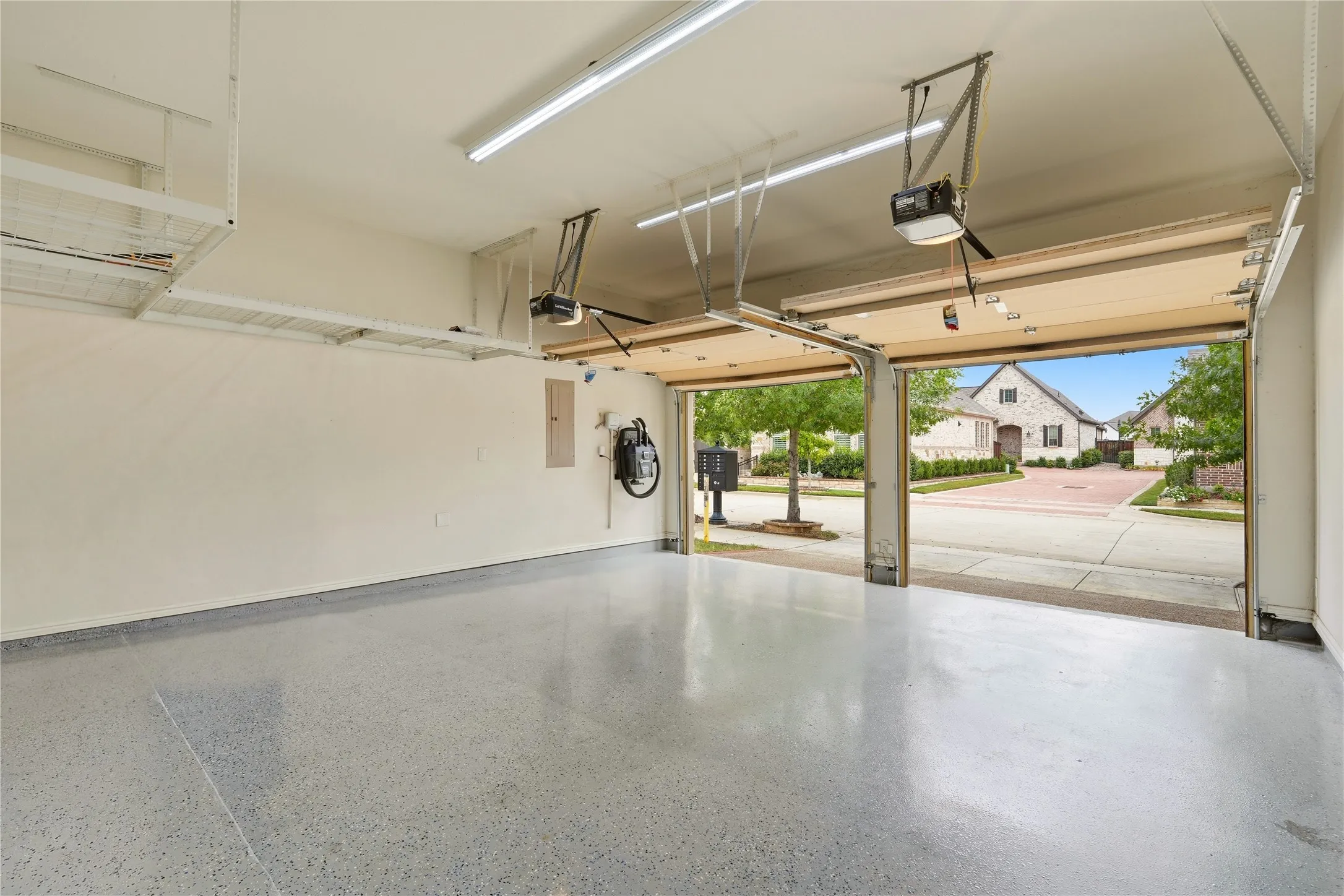 Two-car garage with epoxy-coated flooring, overhead storage racks, and fluorescent lighting