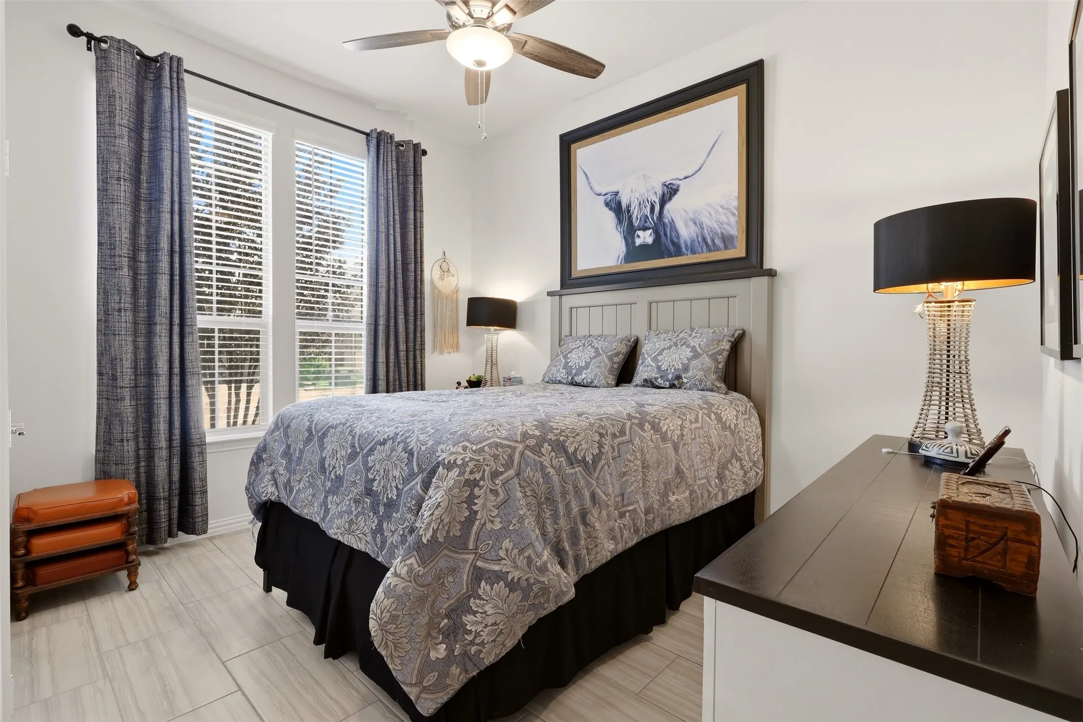 Room featuring two windows with blinds, a ceiling fan with integrated lighting, and light-toned tile flooring