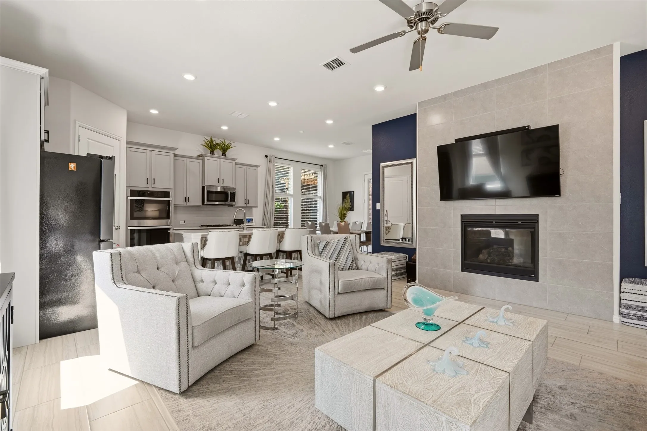 Living area with a tiled fireplace, ceiling fan, and recessed lighting