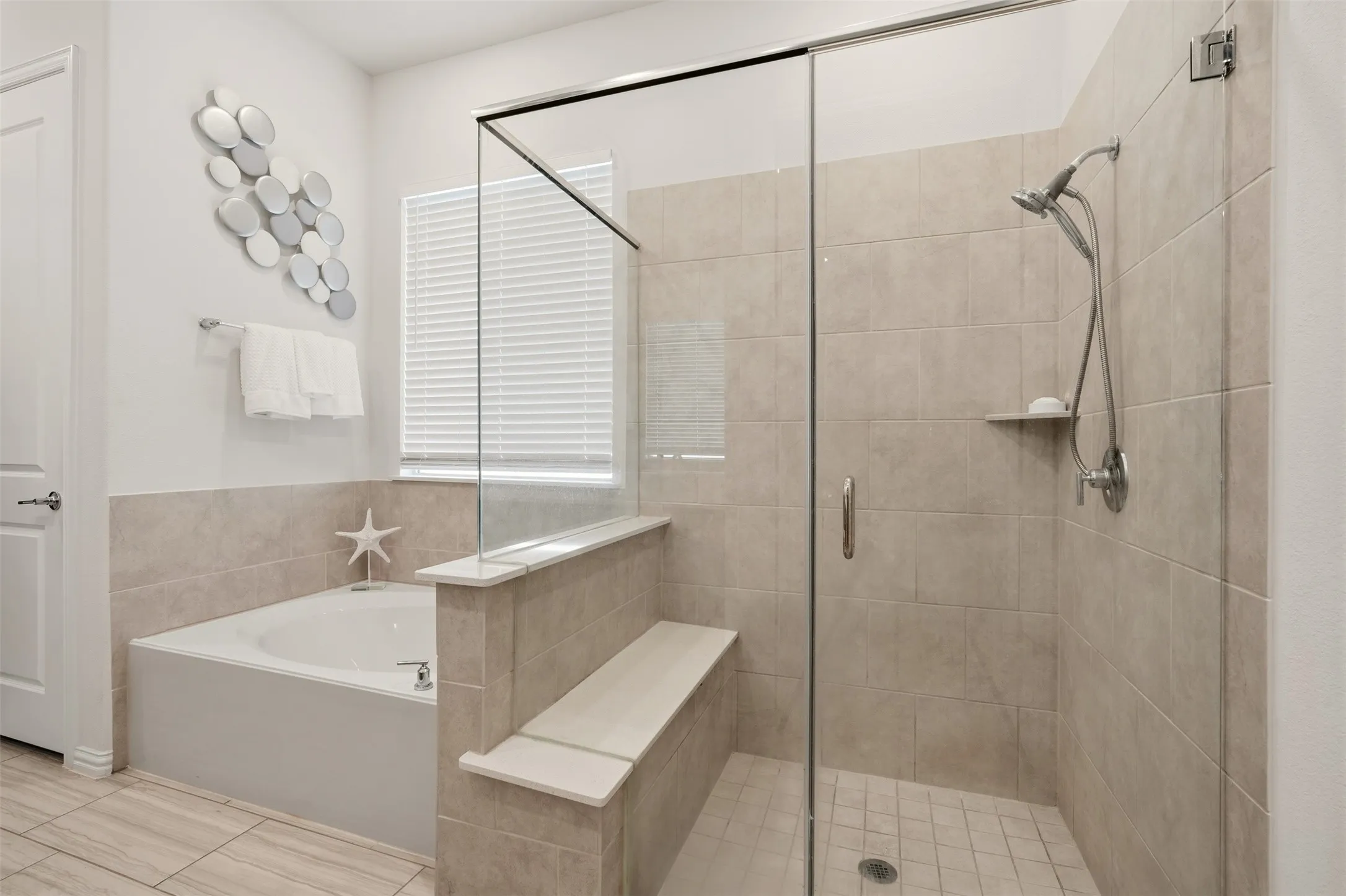 Walk-in shower with clear glass enclosure, tiled walls, and a built-in bench