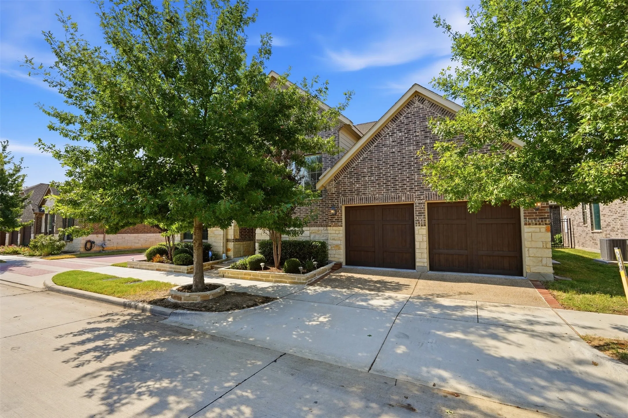 Brick and stone exterior with a two-car garage featuring individual wood-panel doors