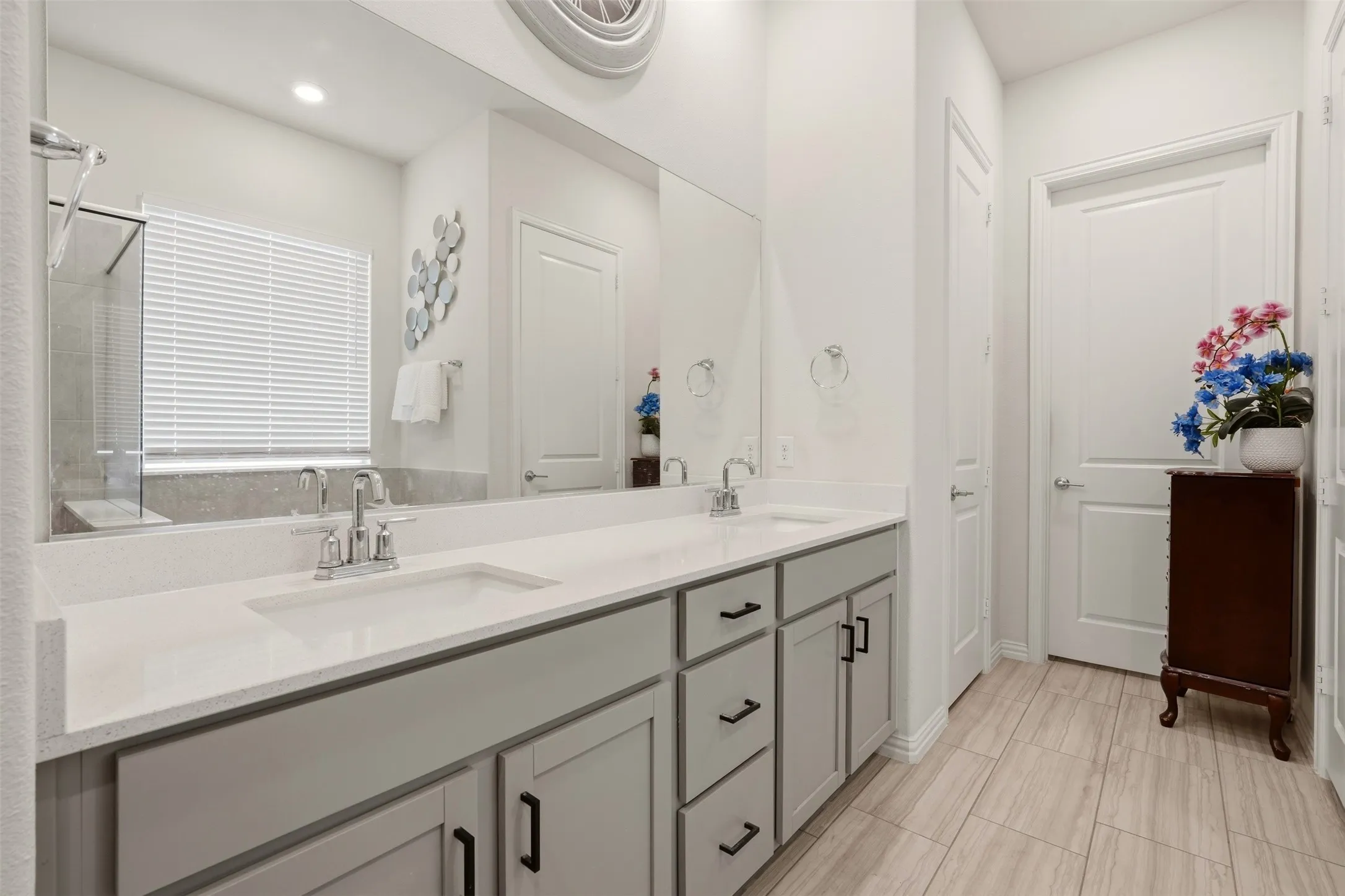Dual vanity with solid surface countertops, light gray cabinetry, and matte black hardware