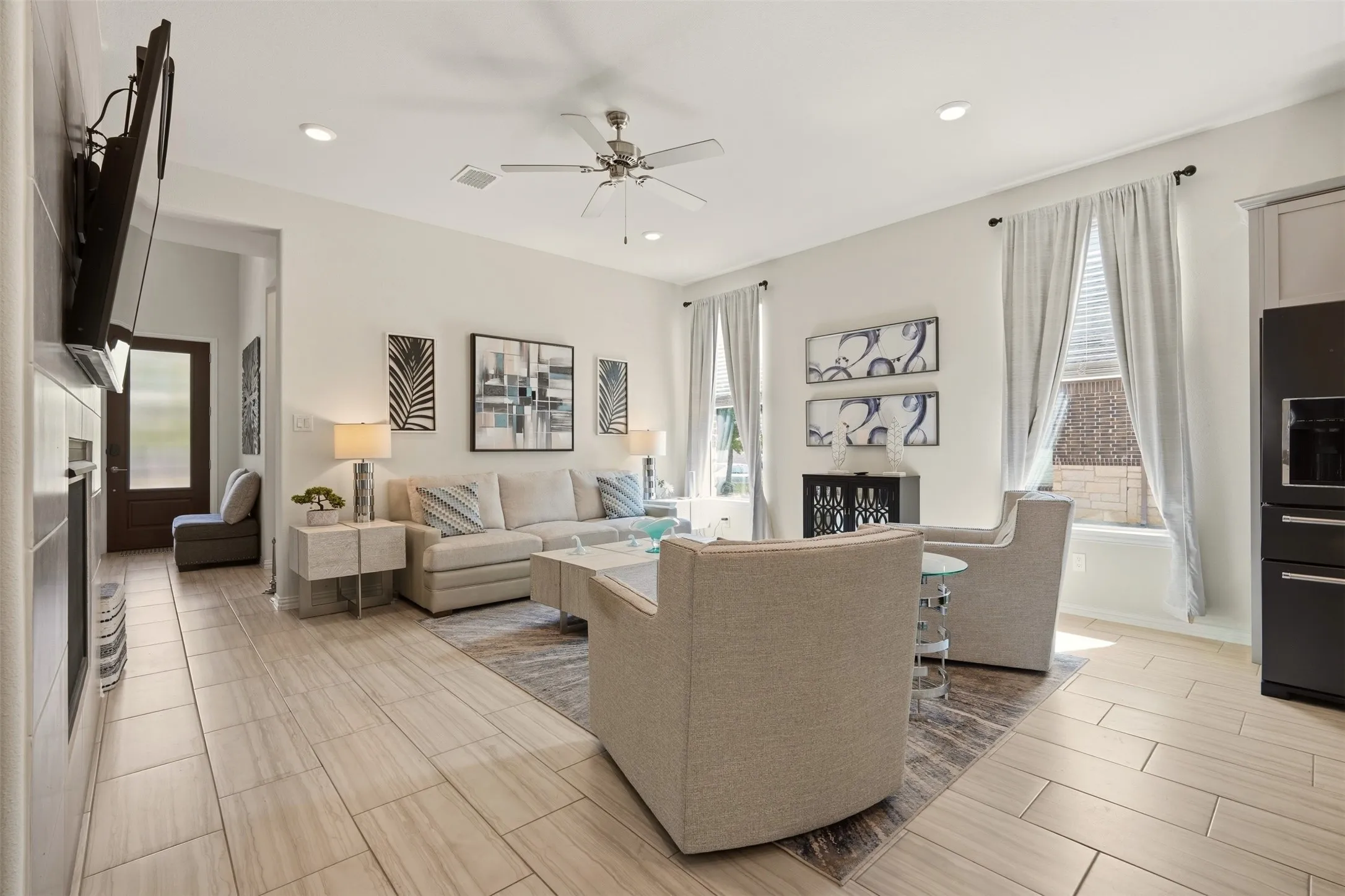 Open-concept living area featuring light-toned tile flooring, recessed lighting, and a ceiling fan