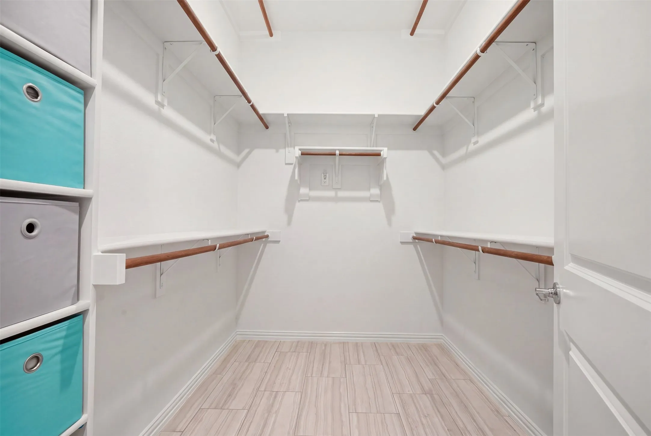 Spacious walk-in closet featuring wood-finish flooring, multiple shelving units, and ample hanging rods