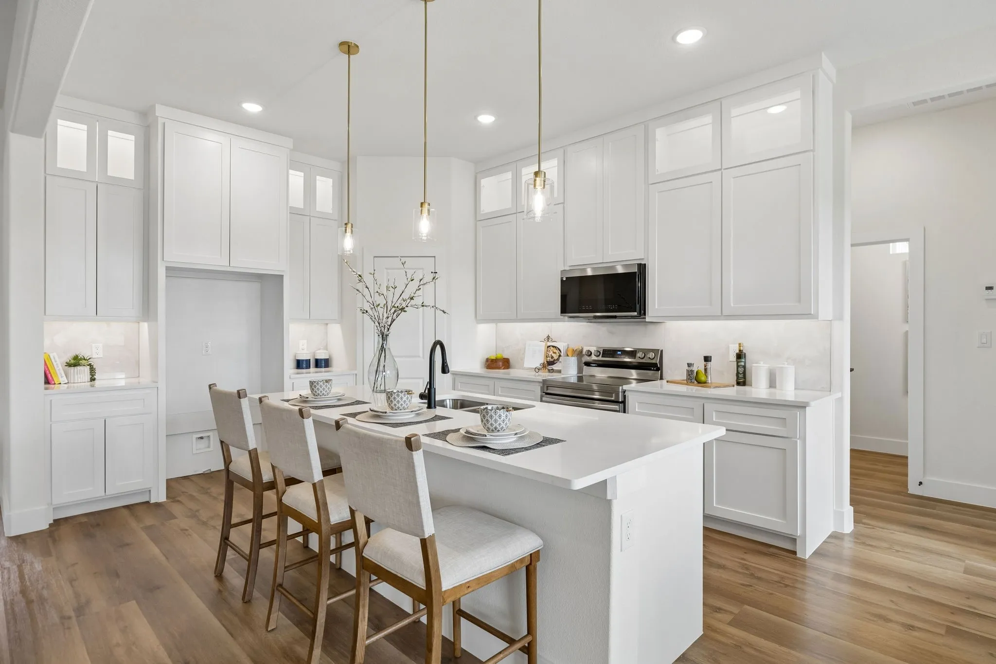 Kitchen featuring white cabinetry, a central island with countertop seating, stainless steel appliances, and pendant lighting
