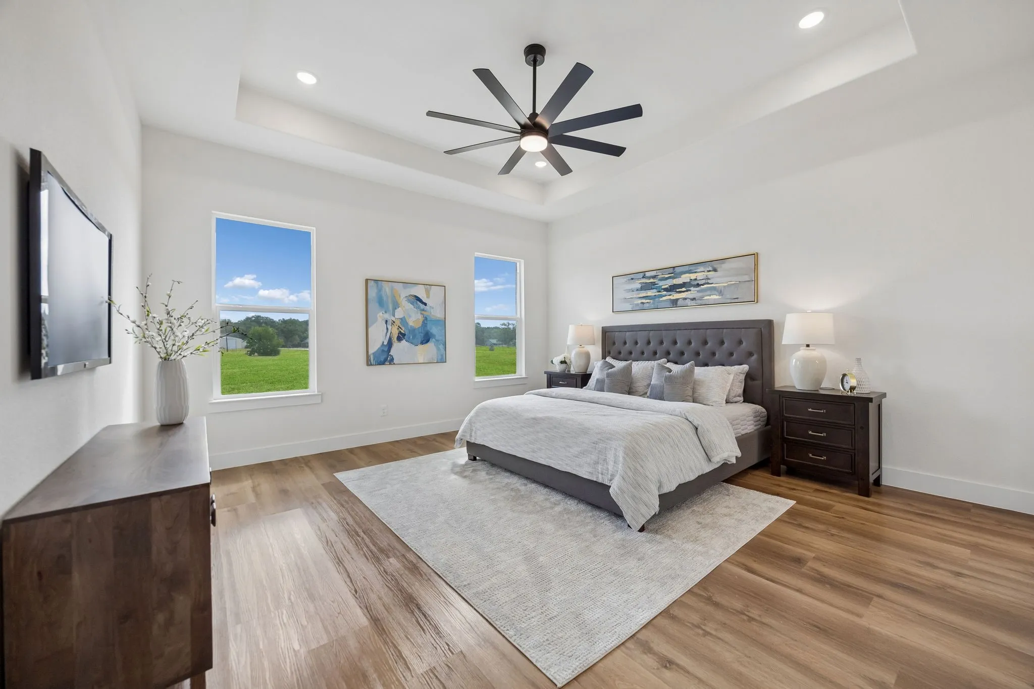 The primary bedroom features a tray ceiling with recessed lighting and a ceiling fan