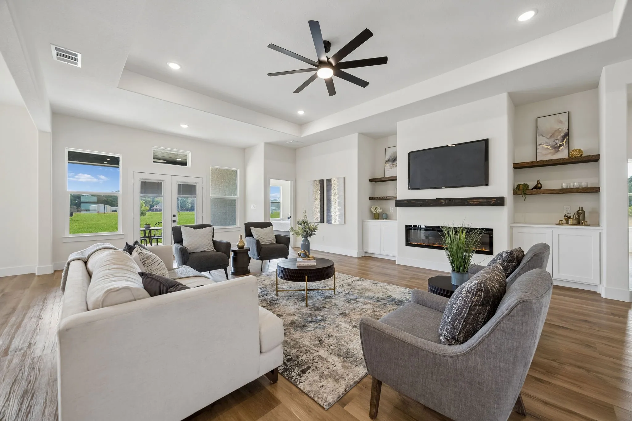 Living room with recessed lighting, a tray ceiling and a ceiling fan