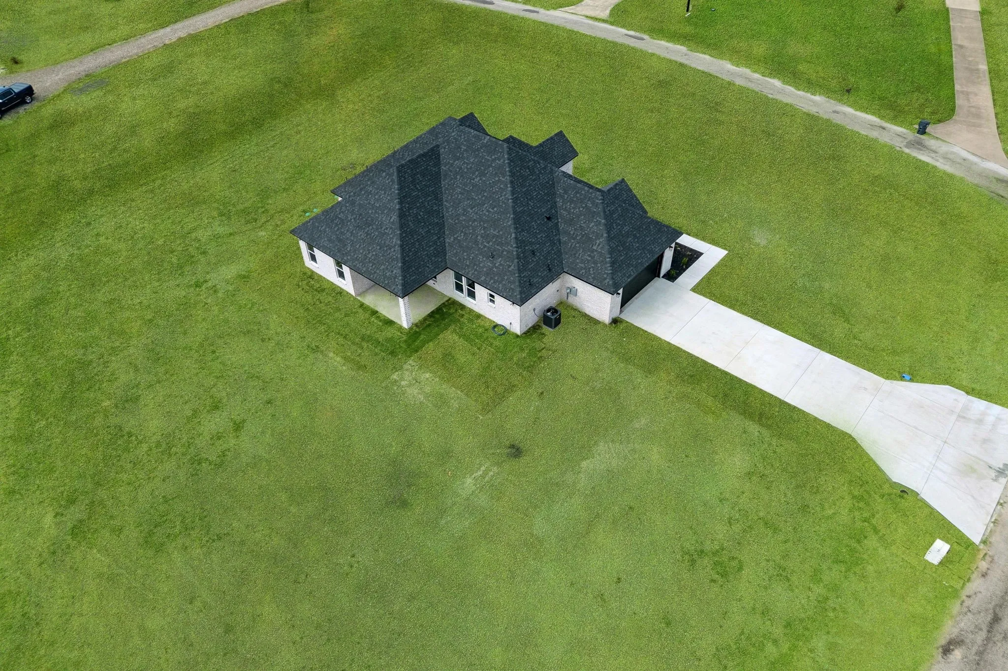 Spacious lot featuring a contemporary single-story residence with a dark shingle roof, light-toned exterior, and an attached garage with a concrete driveway