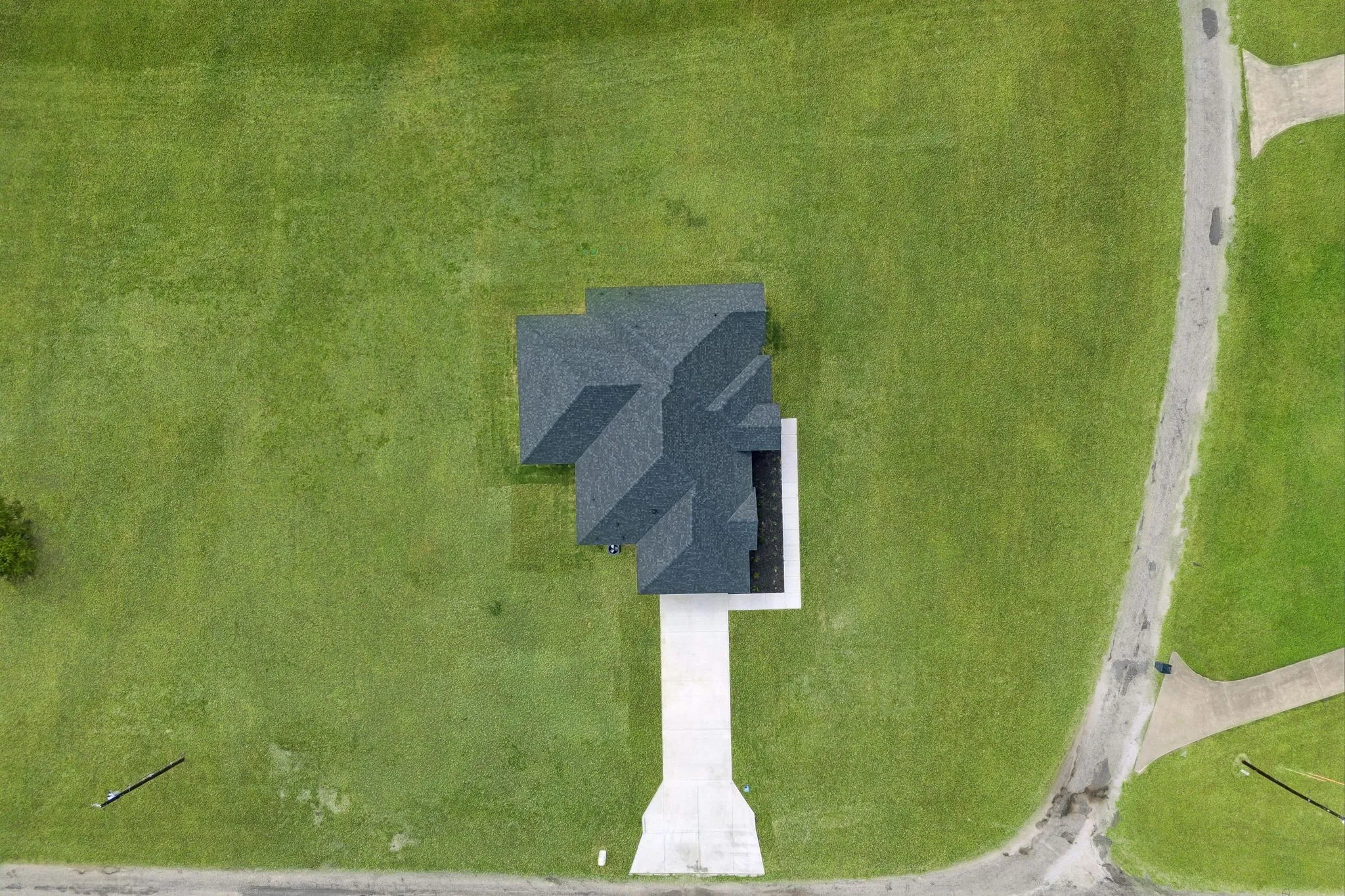 Expansive green space surrounding a property with a multi-gabled roofline and a concrete driveway