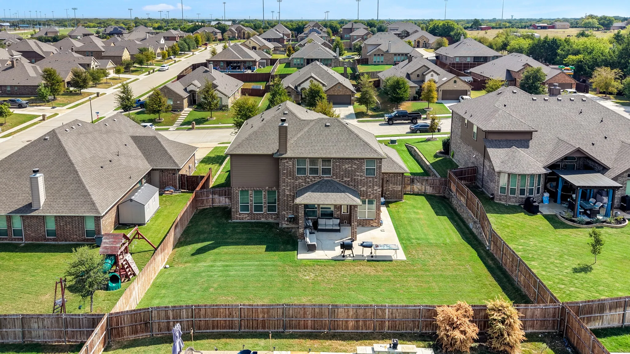 Brick and stone exterior with a covered patio, extensive fenced yard, and well-maintained landscaping