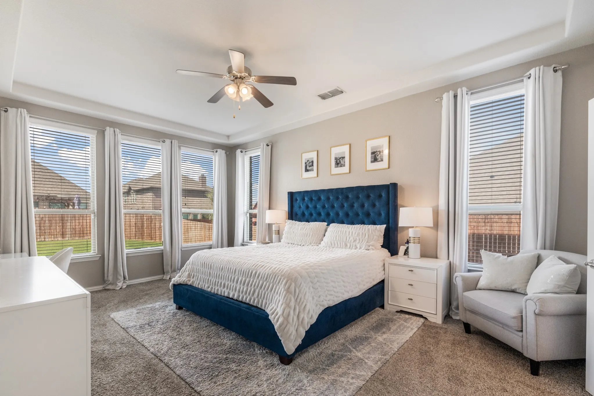 Tray ceiling with recessed lighting, ceiling fan, multiple windows with blinds, and carpeted flooring
