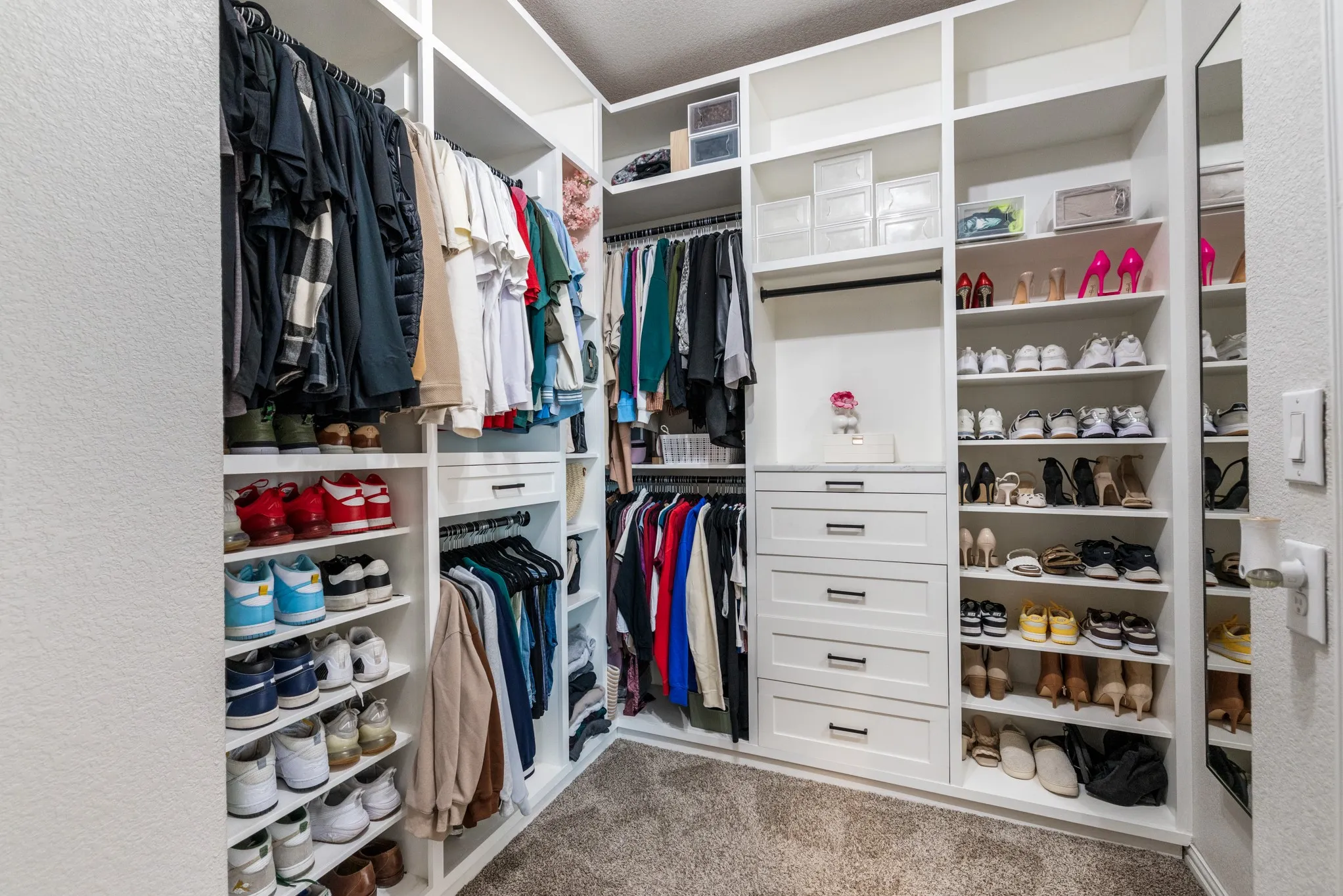 Built-in white custom closet system featuring multiple hanging rods, shelving, and drawer storage