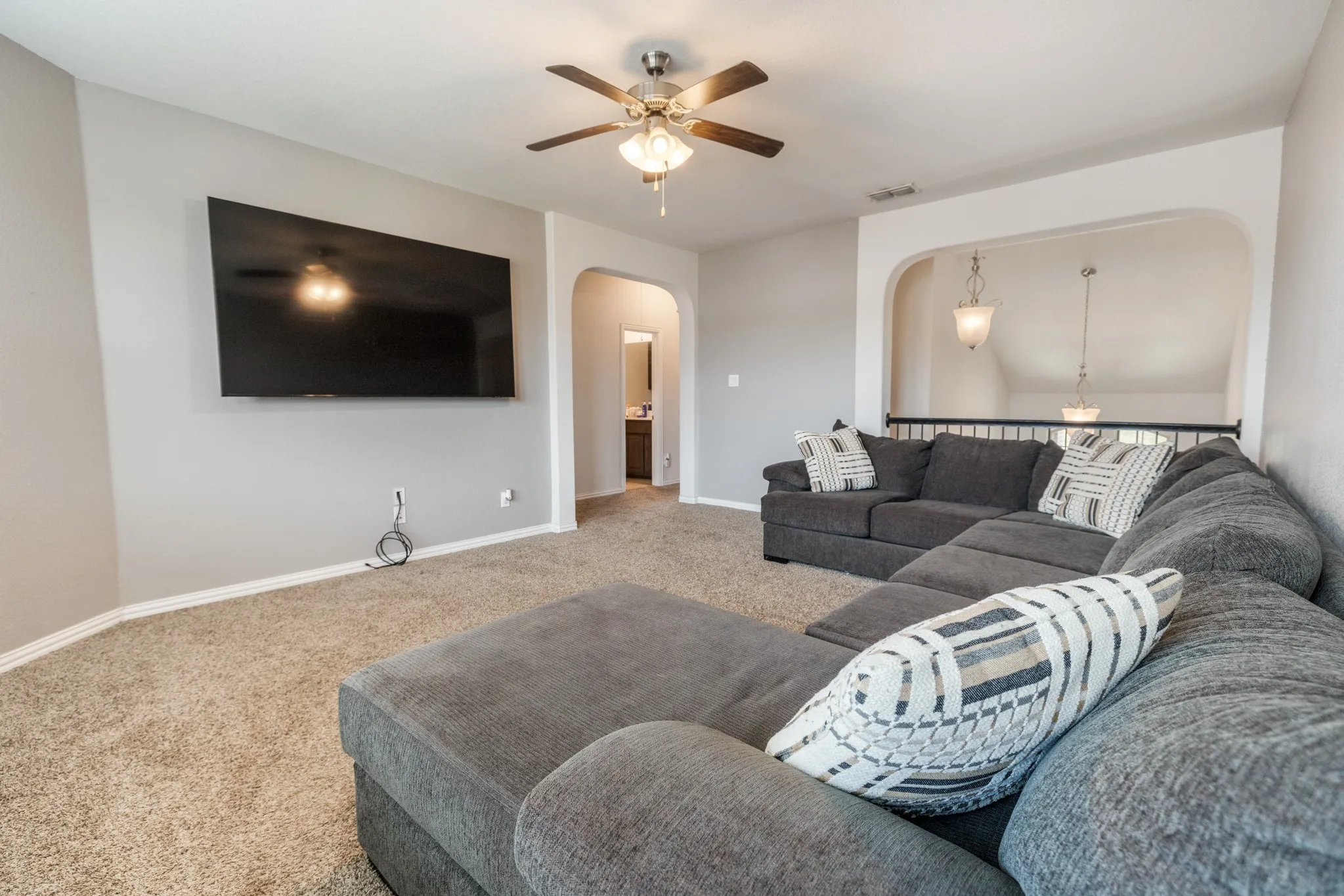 Spacious room featuring carpeting, a ceiling fan with integrated lighting, and an arched doorway
