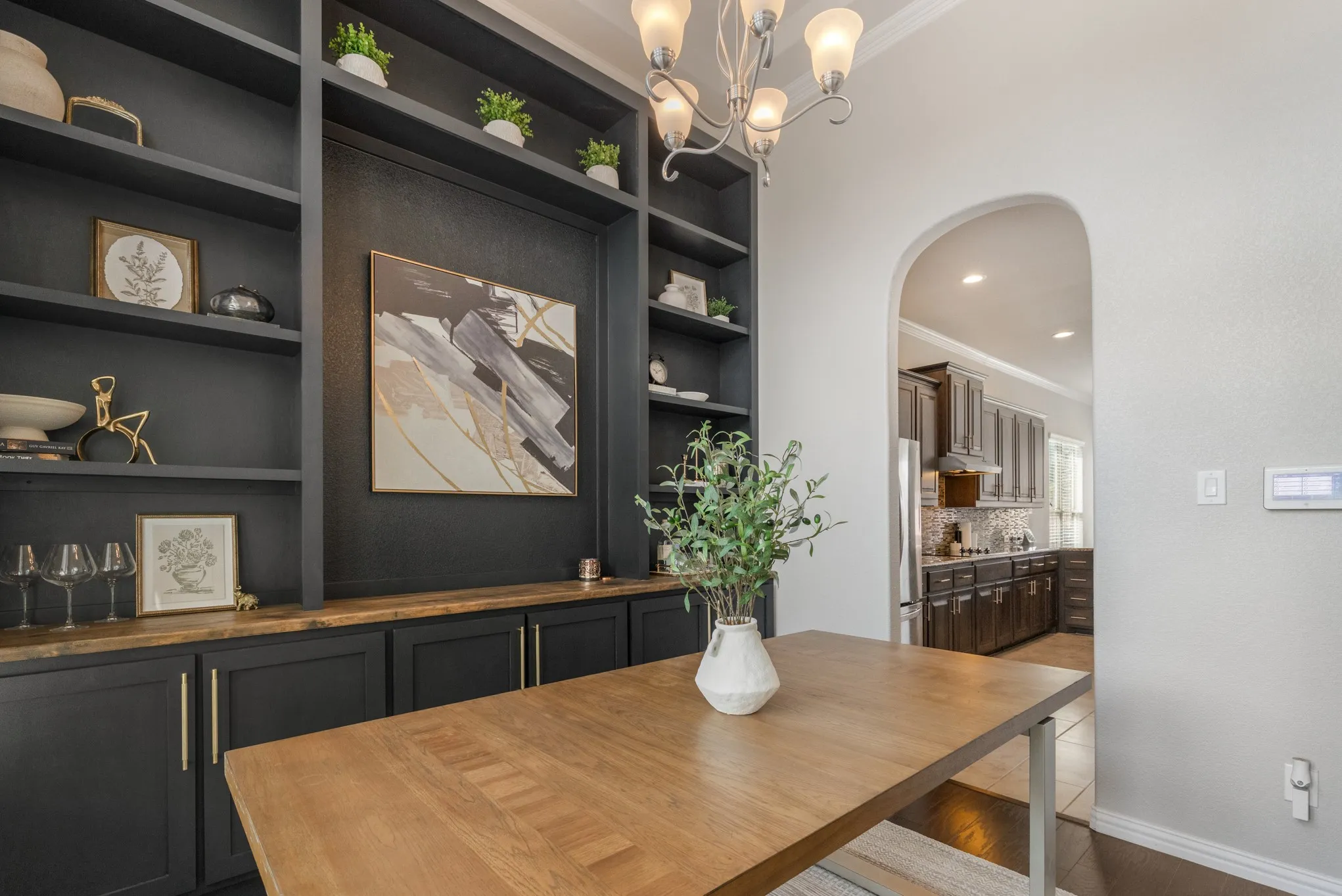 Built-in cabinetry with wood-finish countertop, arched doorway, and overhead chandelier