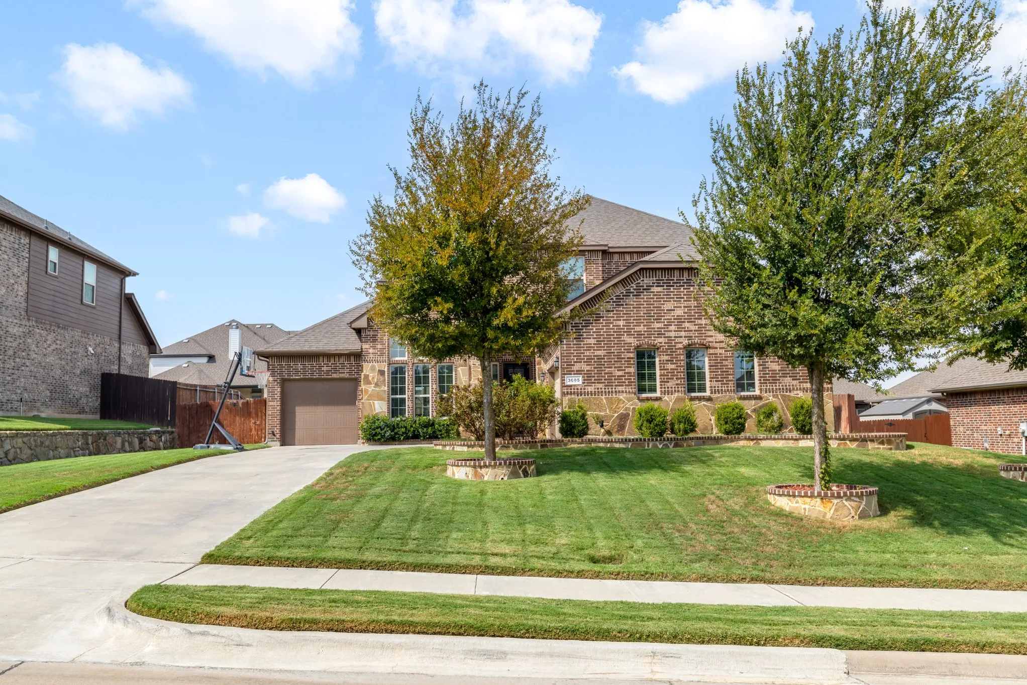 Brick and stone facade residence with a concrete driveway and an attached garage