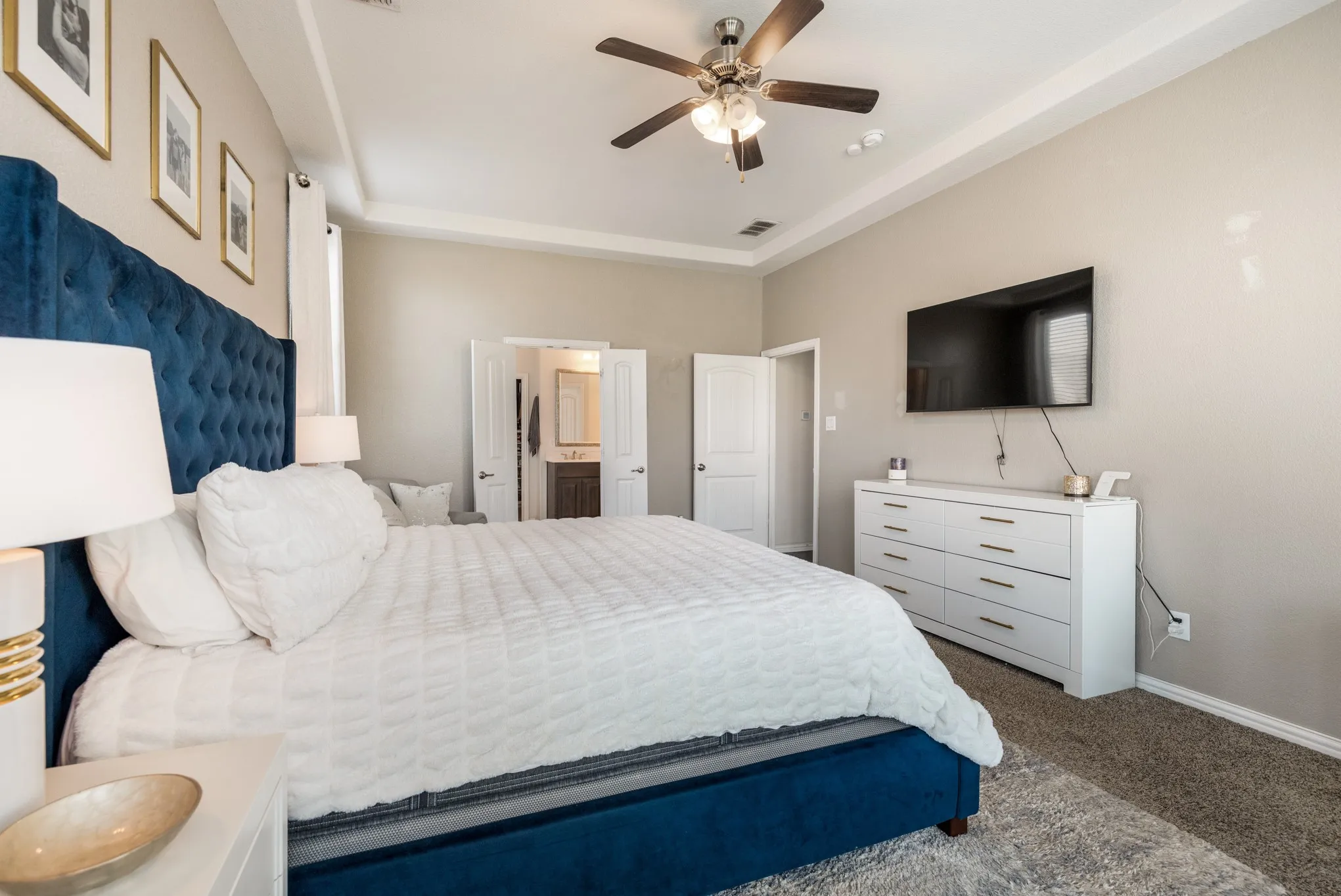 Tray ceiling with crown molding, ceiling fan, carpeted flooring, and light-toned wall paint
