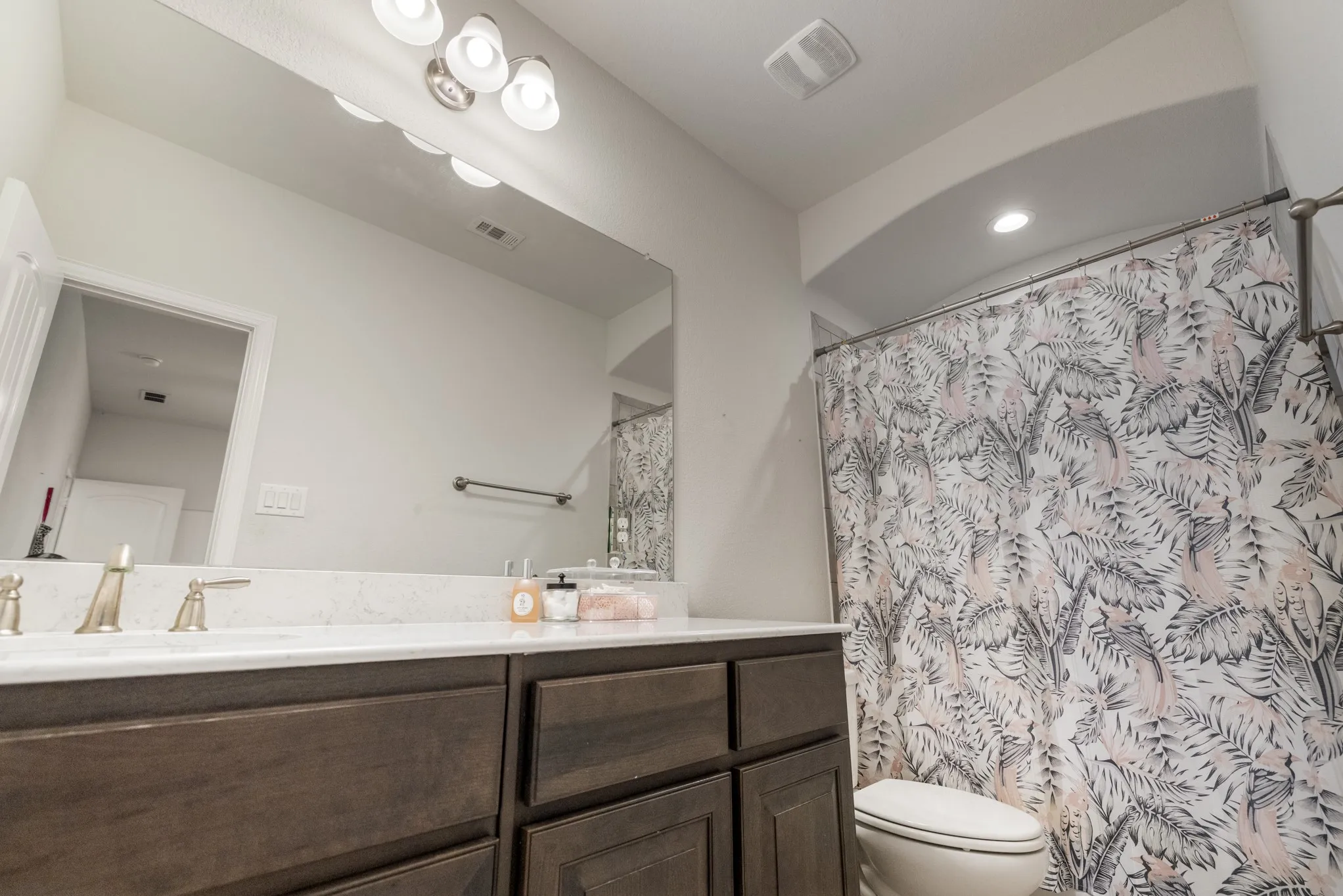 Full vanity mirror with decorative light fixture, white countertop, dark wood-finish cabinetry, and brushed nickel faucet