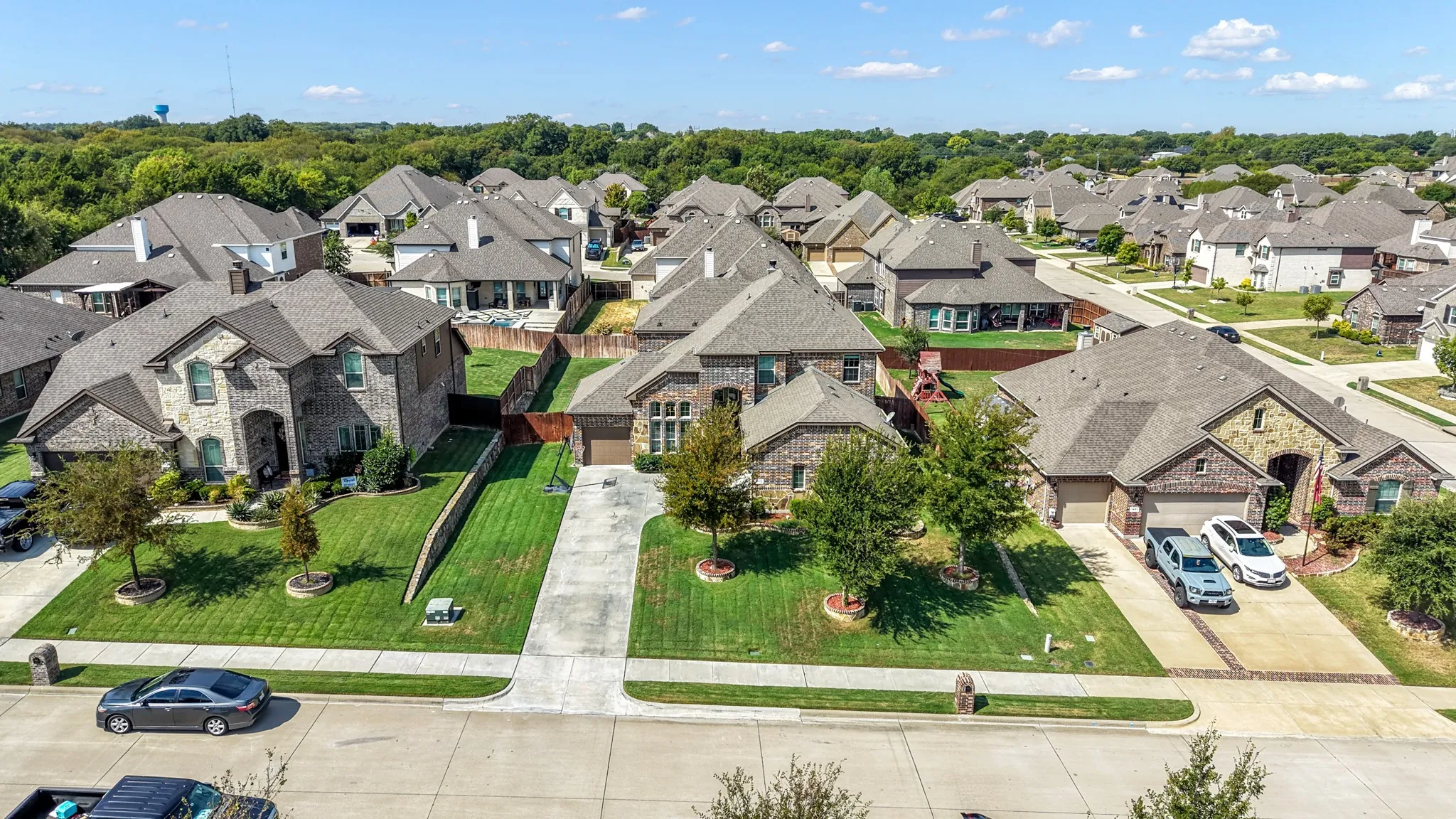 Brick and stone exterior with a gabled roofline, concrete driveway, attached garage, and manicured landscaping