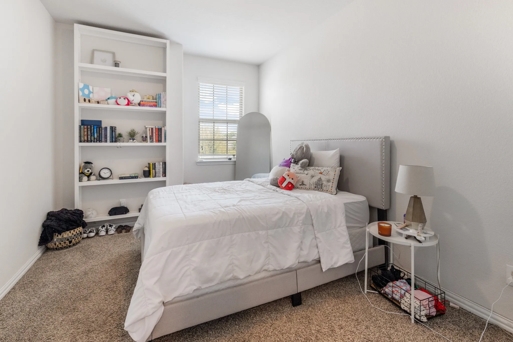 Built-in shelving unit, window with blinds, and carpeted flooring