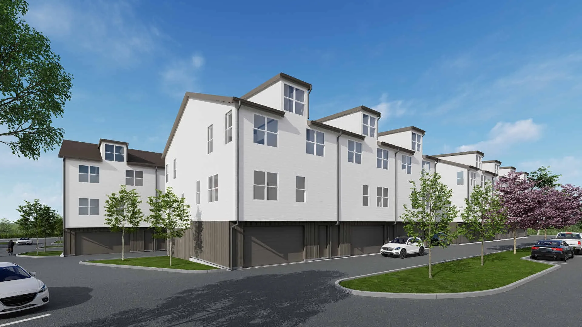 Modern townhouse exterior with white siding and dark trim, multiple dormer windows, attached garage doors, and landscaped common areas