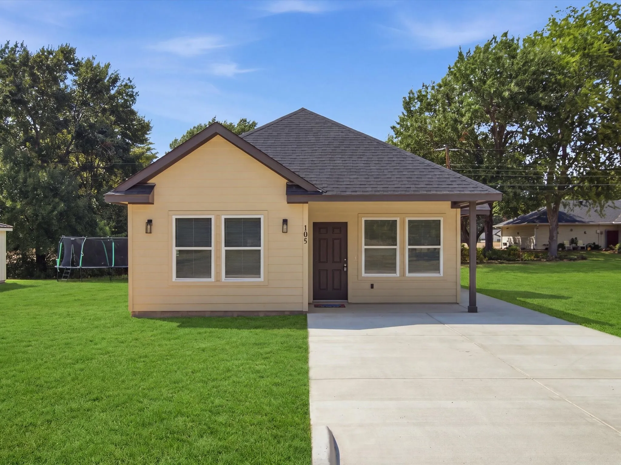 Single-story home featuring a light-colored siding exterior, dark shingle roof, and a concrete driveway
