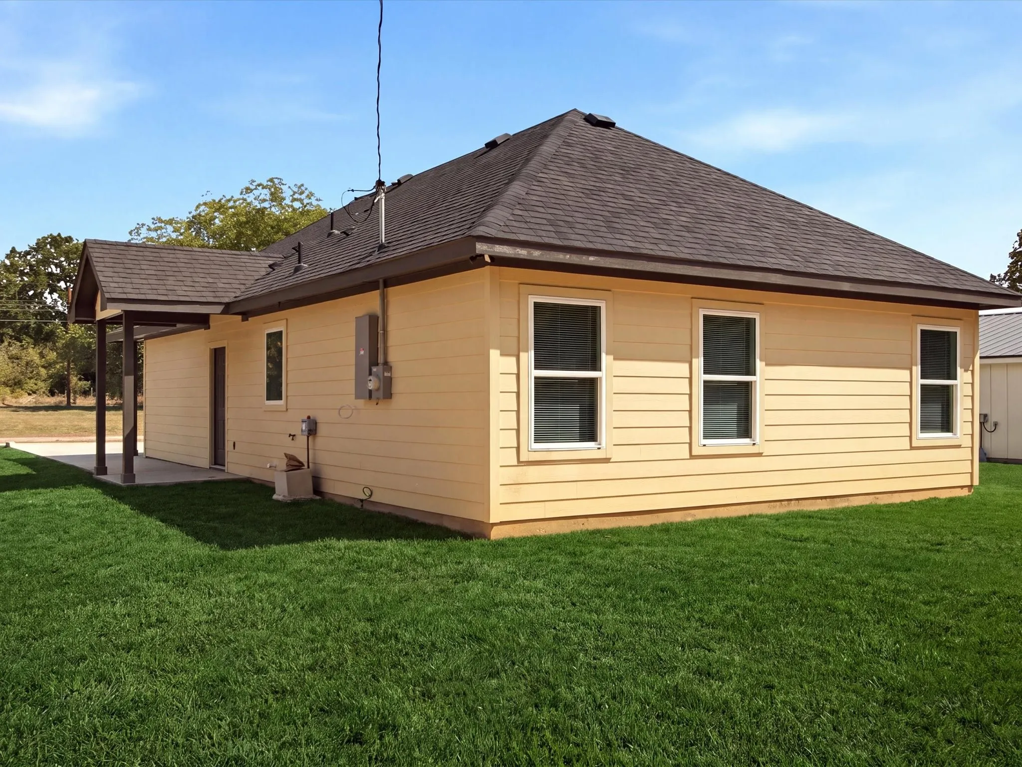 Exterior featuring horizontal siding, multiple windows with white frames, a covered patio, and a shingled roof