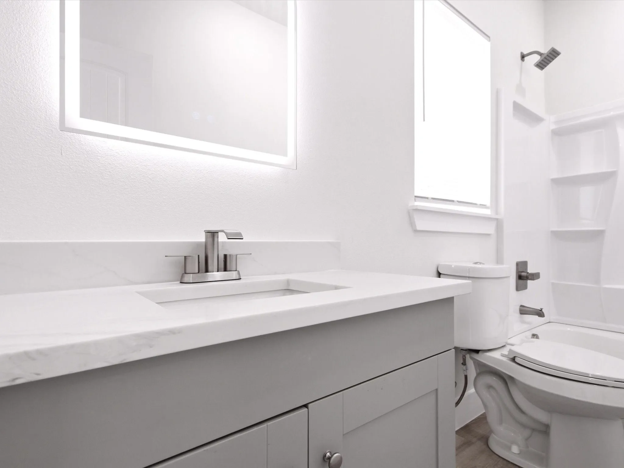 Vanity with gray cabinetry, integrated sink, and brushed nickel faucet