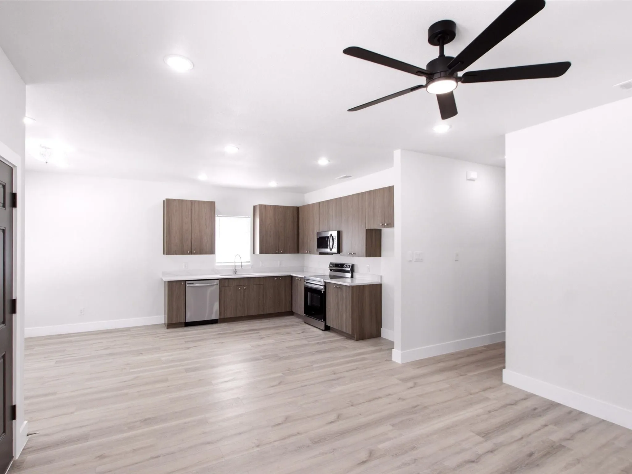 Open-concept living space with wood-finish flooring, recessed lighting, and a contemporary ceiling fan