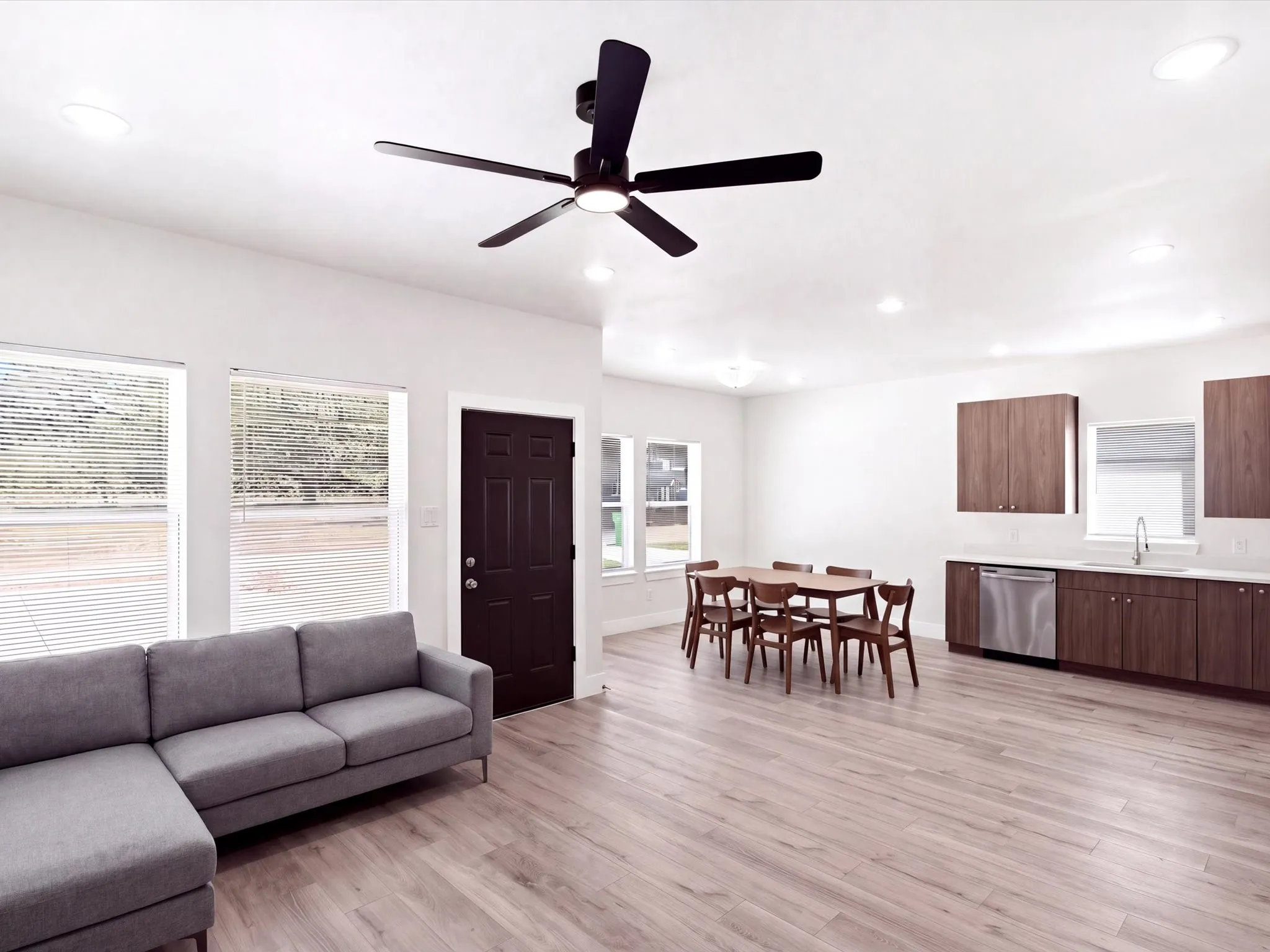 Recessed lighting, wood-finish flooring, dark wood-tone cabinetry, stainless steel dishwasher, and a ceiling fan