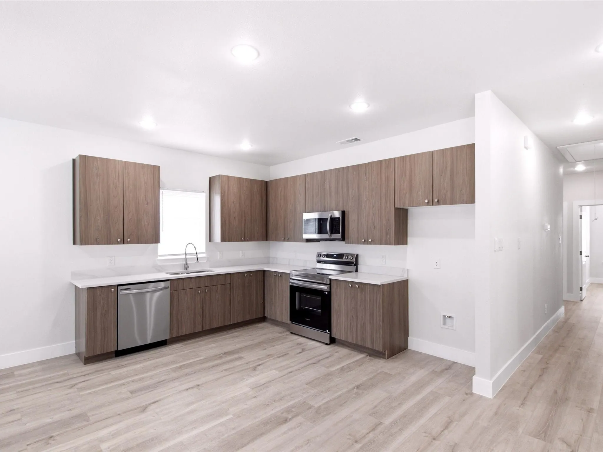 Kitchen with wood-finish cabinetry, white countertops, subway tile backsplash, and stainless steel appliances