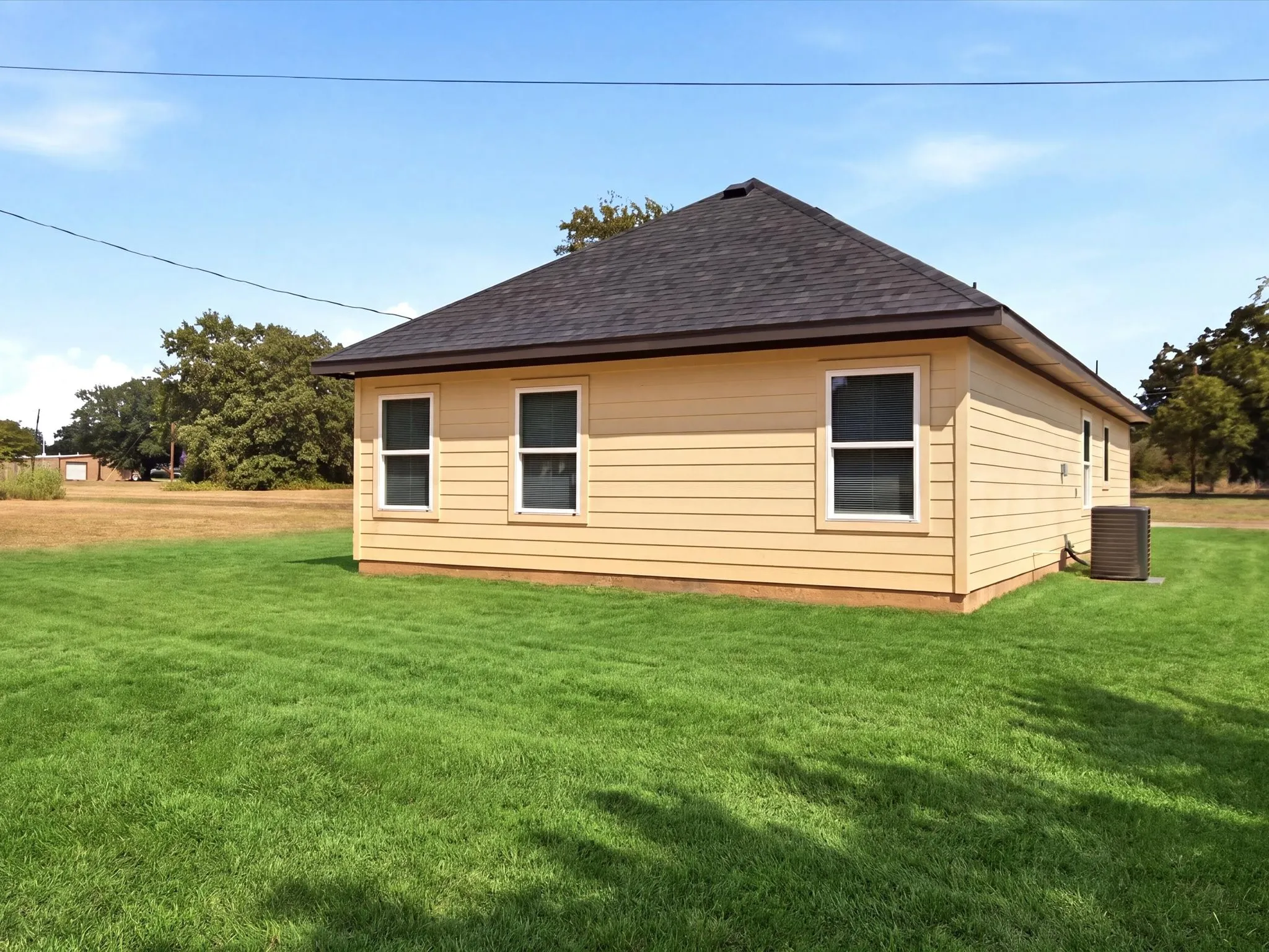 Exterior featuring horizontal siding, multiple windows with white trim, a dark shingle roof, and a visible HVAC unit