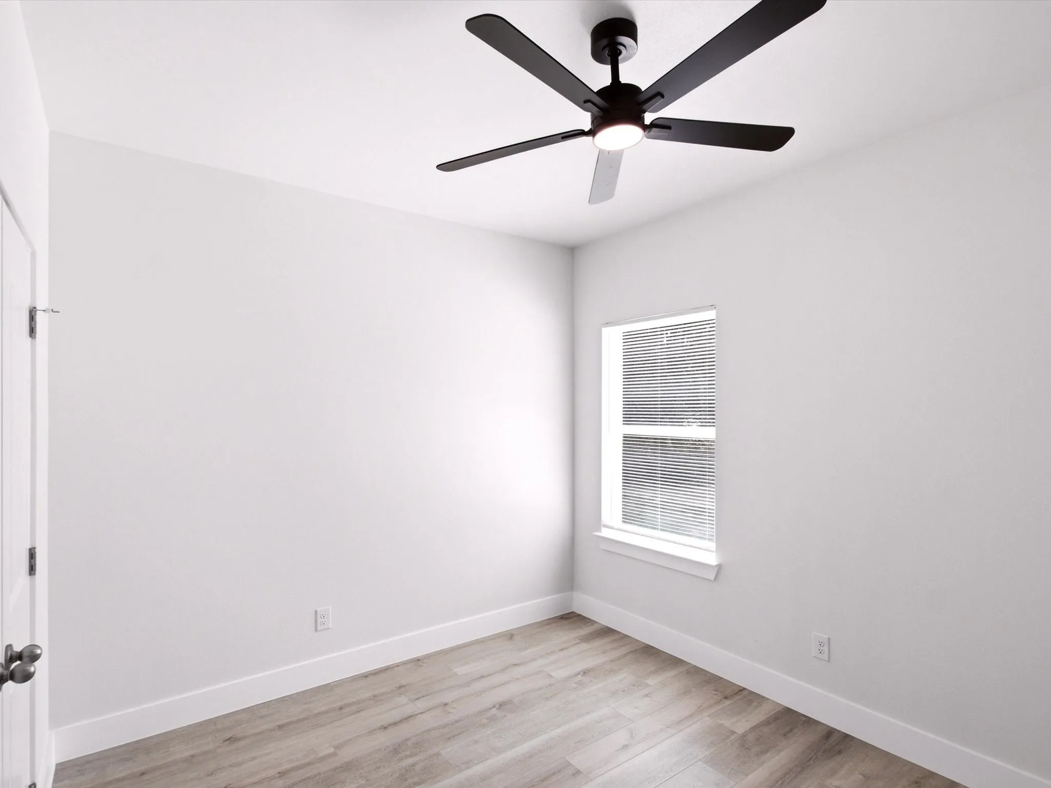 Neutral paint palette with wood-finish flooring, a window with blinds, a white door, and a ceiling fan with integrated lighting