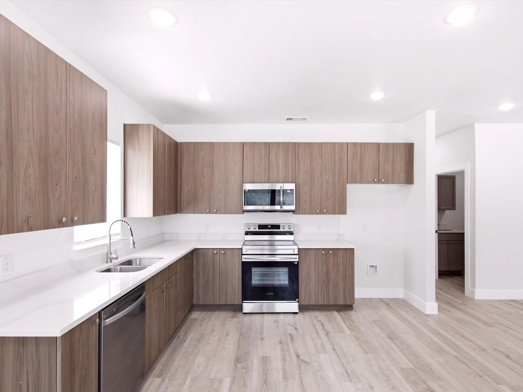 Kitchen featuring wood-finish cabinetry, stainless steel appliances, white countertops, and light wood-finish flooring