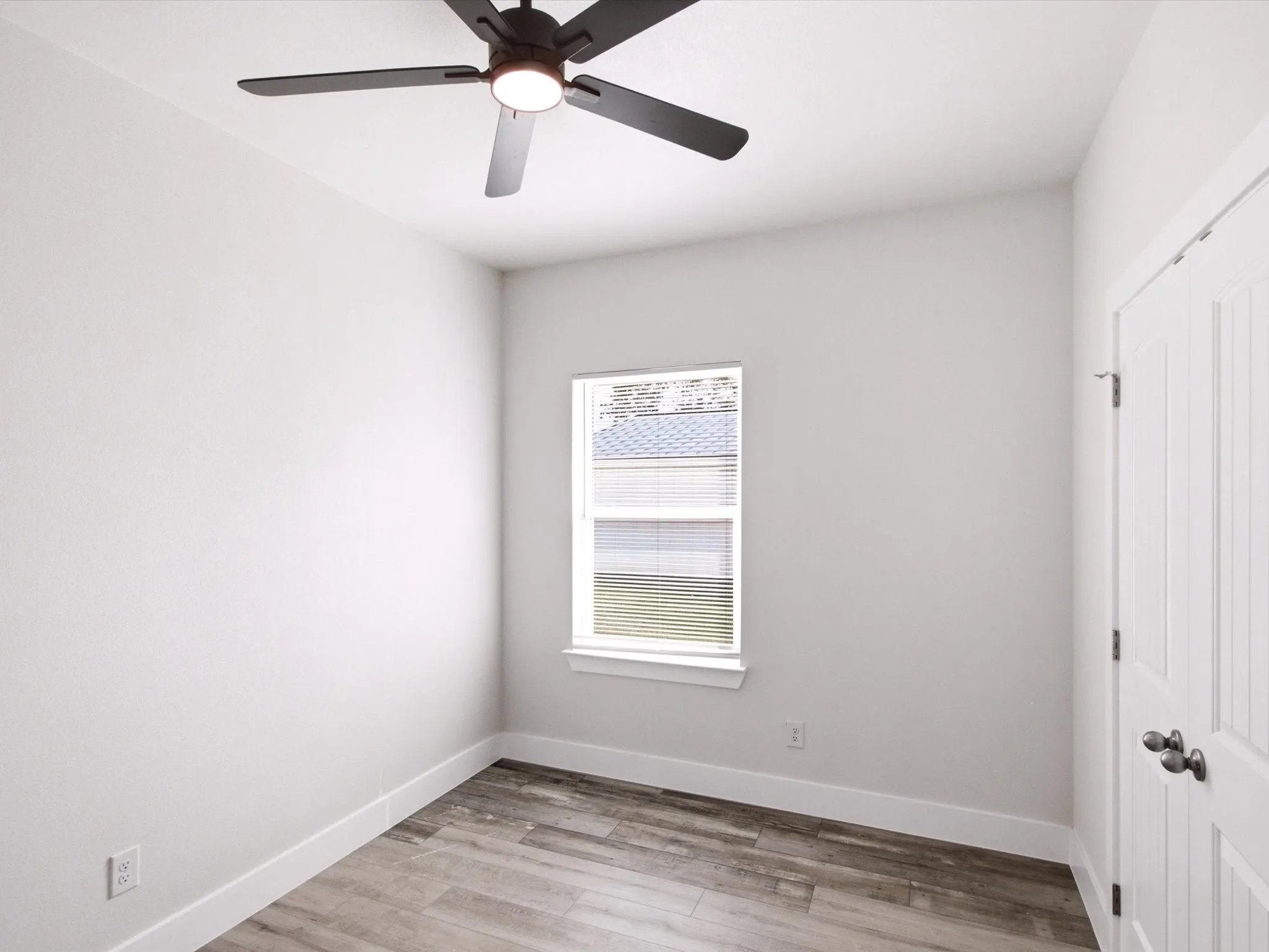 Wood-finish flooring, white walls, ceiling fan with integrated lighting, single window, and white interior door
