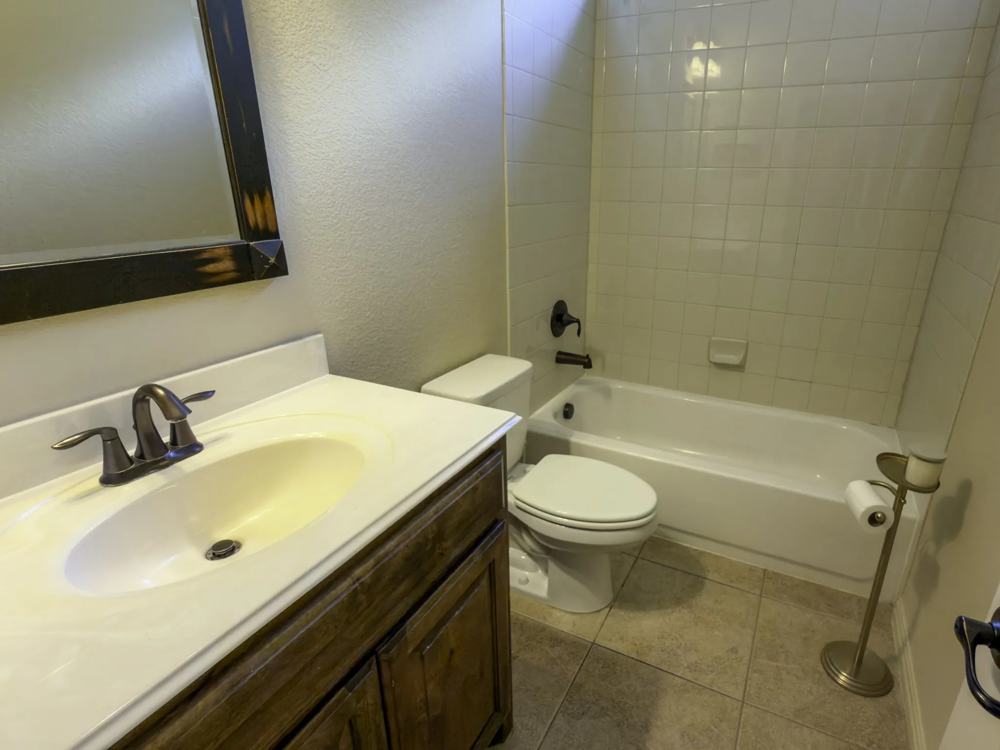 Bathroom featuring a vanity with an integrated sink, a dark wood-finish cabinet, a full-size bathtub, and tiled shower surround