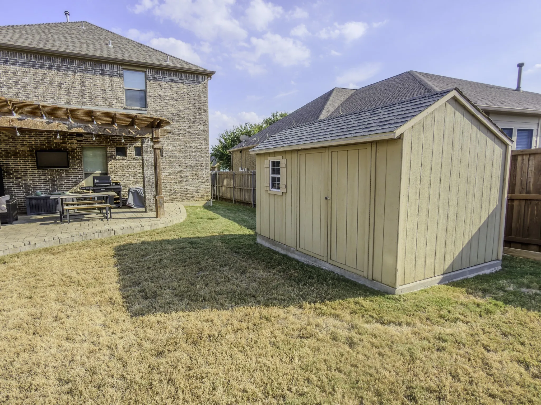 Outdoor patio with a wood pergola, brick exterior, and a detached storage shed