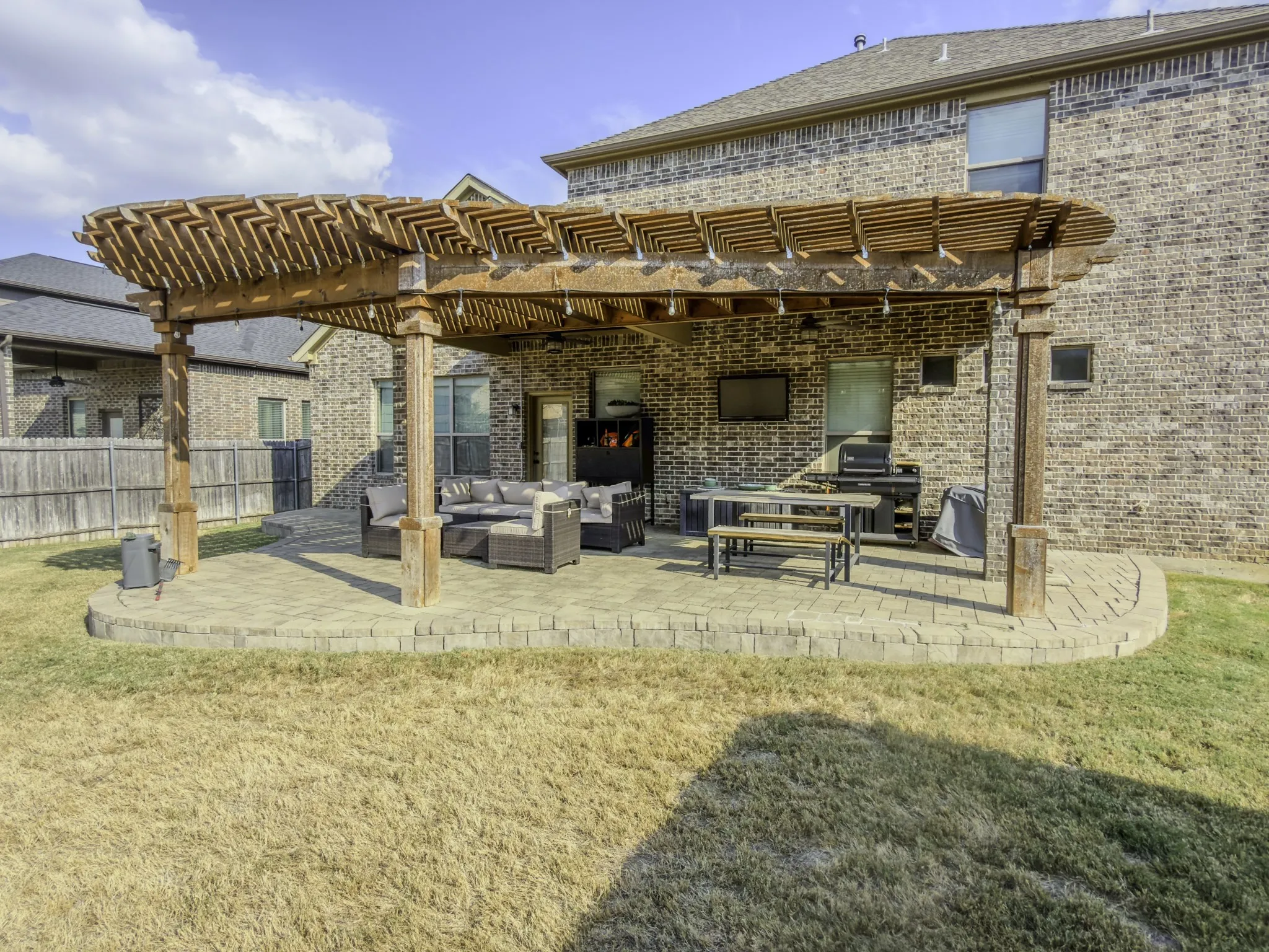Extended paver patio with a wood pergola structure