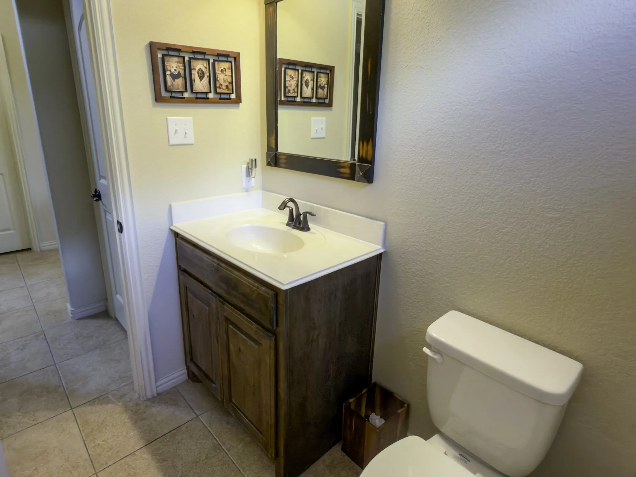 Wood-finish vanity with an integrated sink, bronze-finish faucet, and coordinating framed mirror