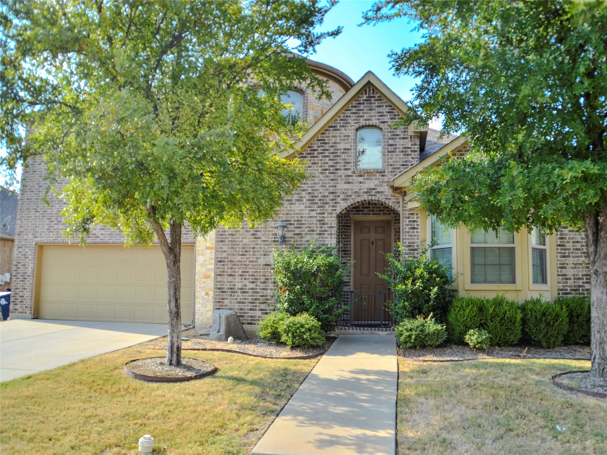 Brick exterior facade with stone accents, arched entryway, bay window, and attached garage