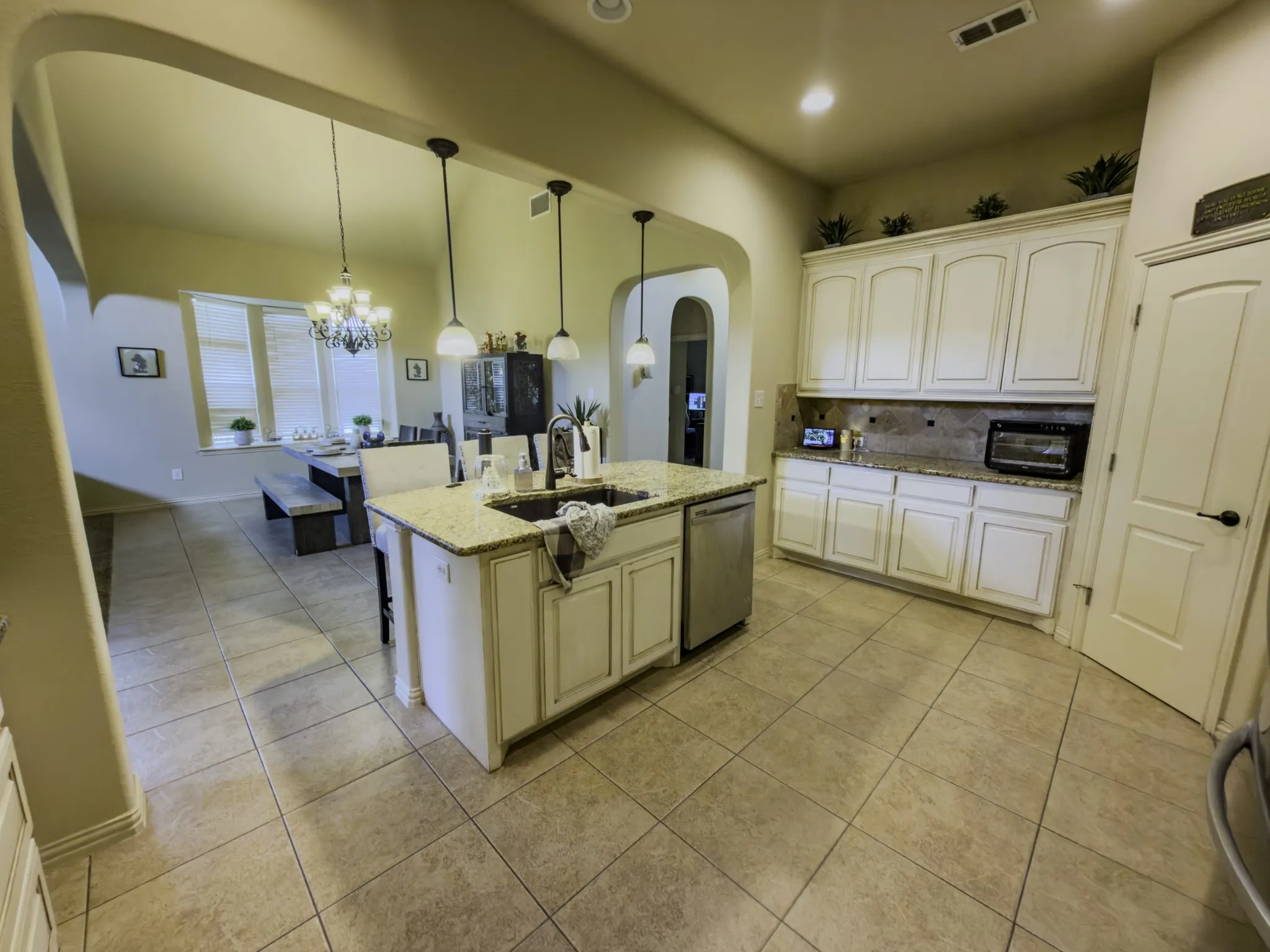 Kitchen featuring a central island with sink, pendant lighting, and granite countertops