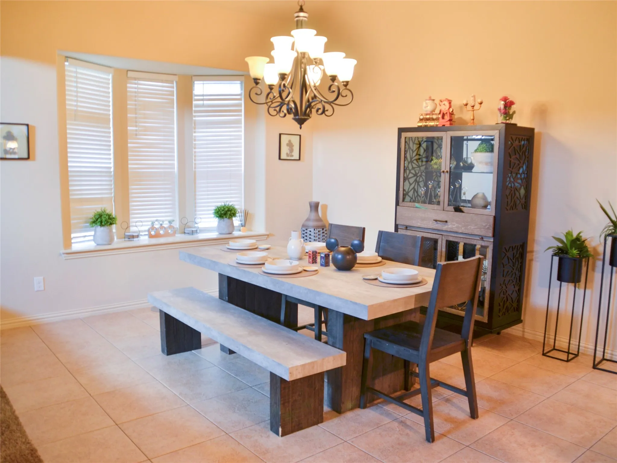 Bay window with louvered blinds, tile flooring, and an ornate chandelier
