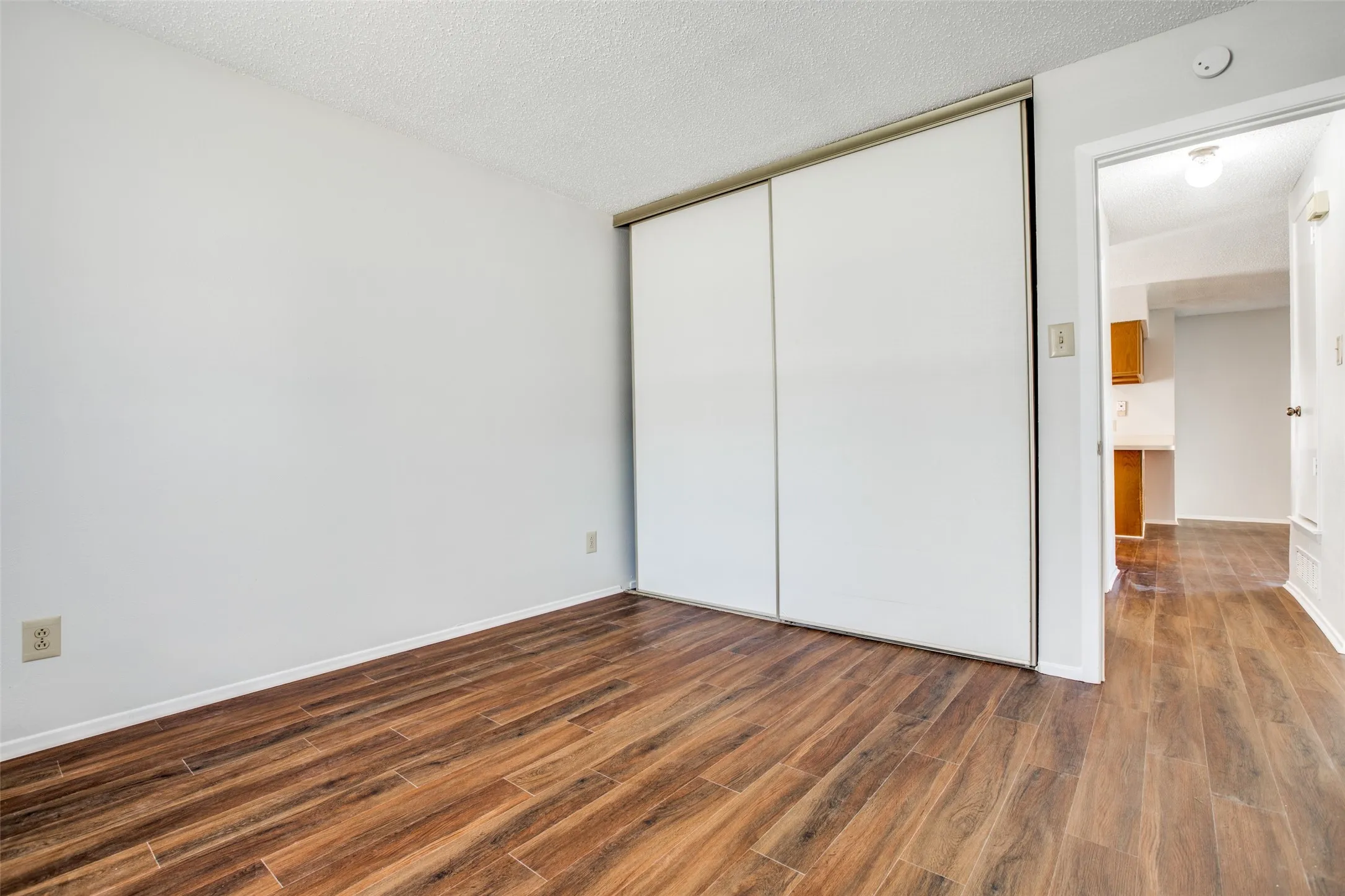 Wood-finish flooring, white walls, and a built-in closet with sliding doors