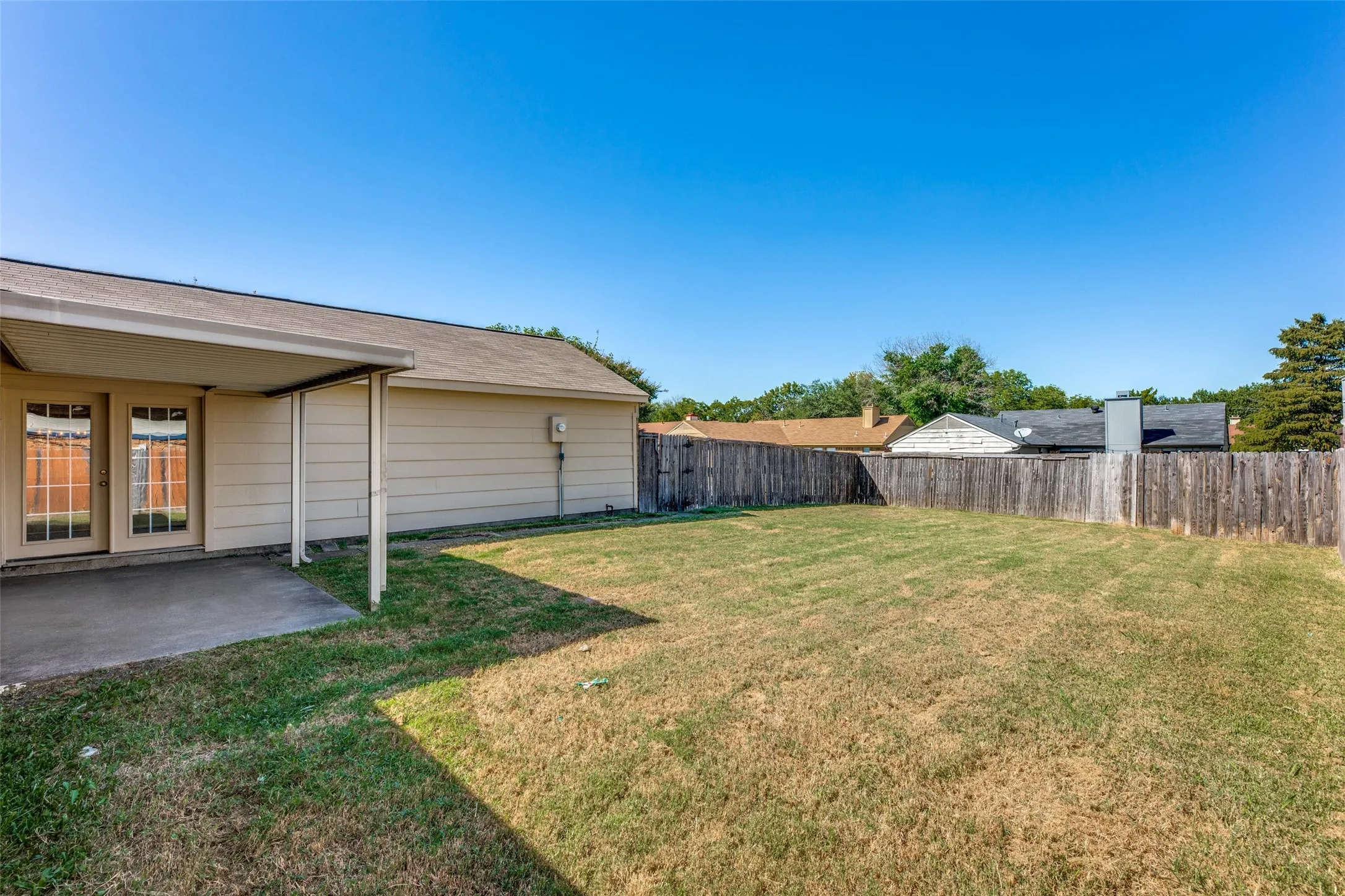 Expansive backyard featuring a wood fence and a concrete patio