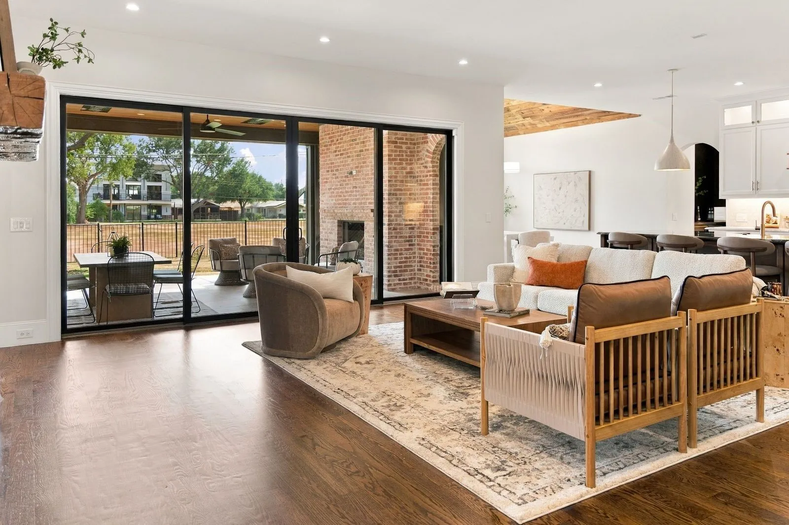 Expansive living area featuring wood-finish flooring, recessed lighting, and a brick-clad fireplace