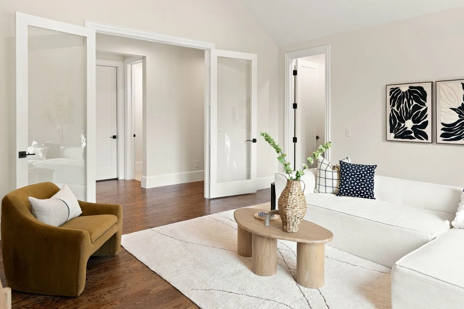 Rich wood-finish flooring, vaulted ceiling, and dual glass-panel doors with matte black hardware